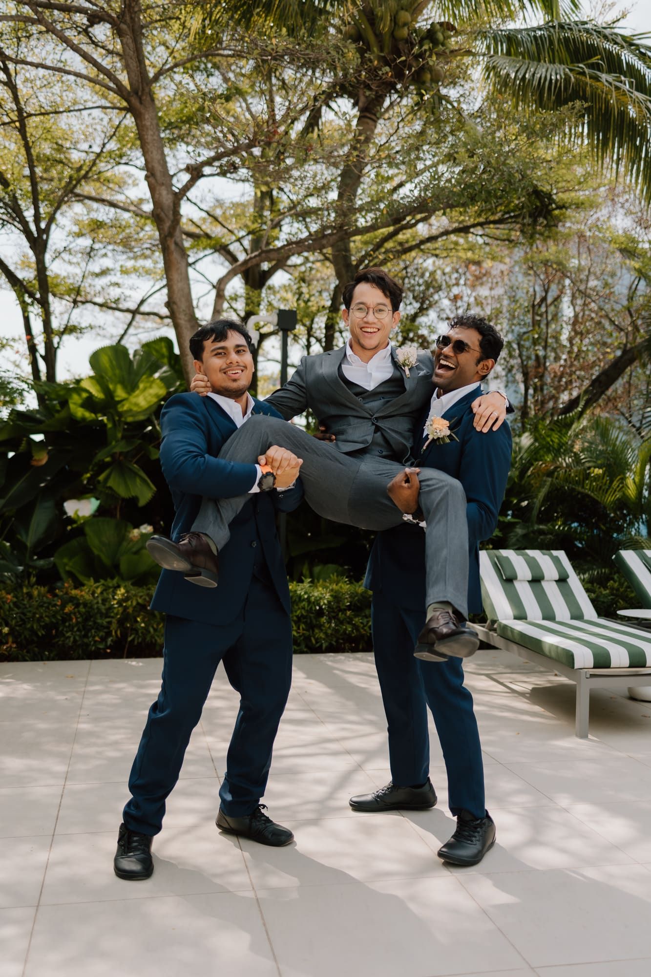 A sequence of playful dance moves performed by three people in suits on an outdoor patio with palm trees.