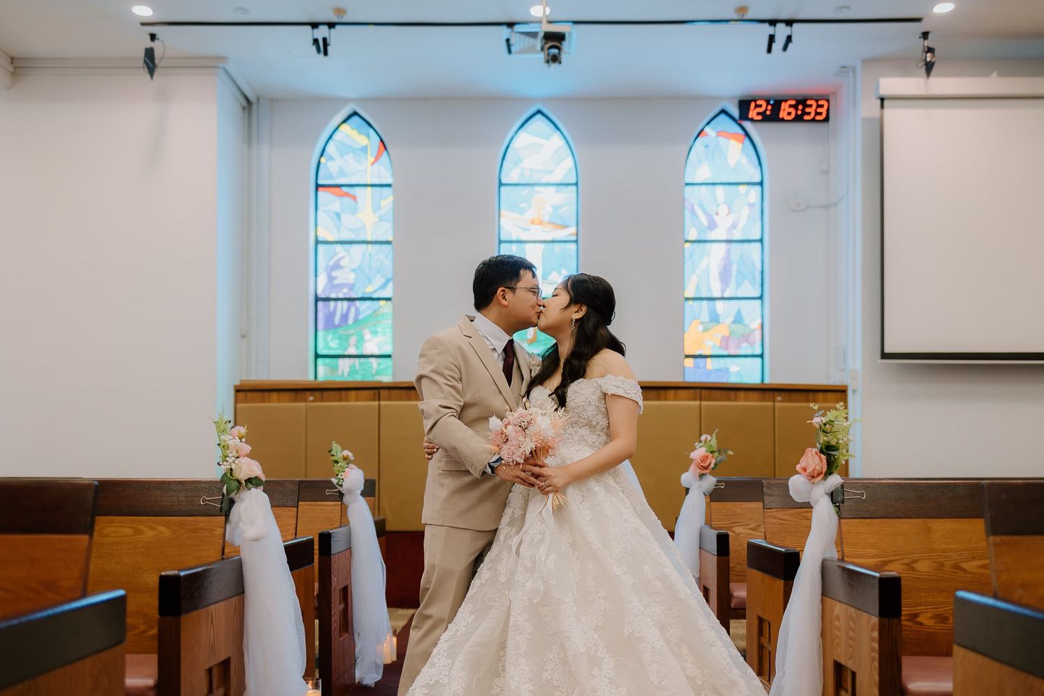 Romantic wedding portrait in church with stained glass windows and arched doorways.