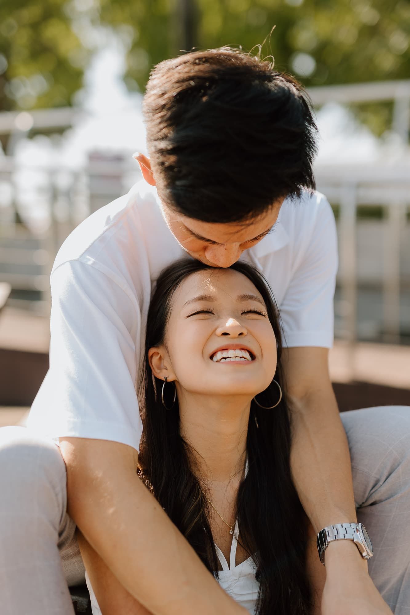A tender moment captured between a couple in white outfits on a sunny day.