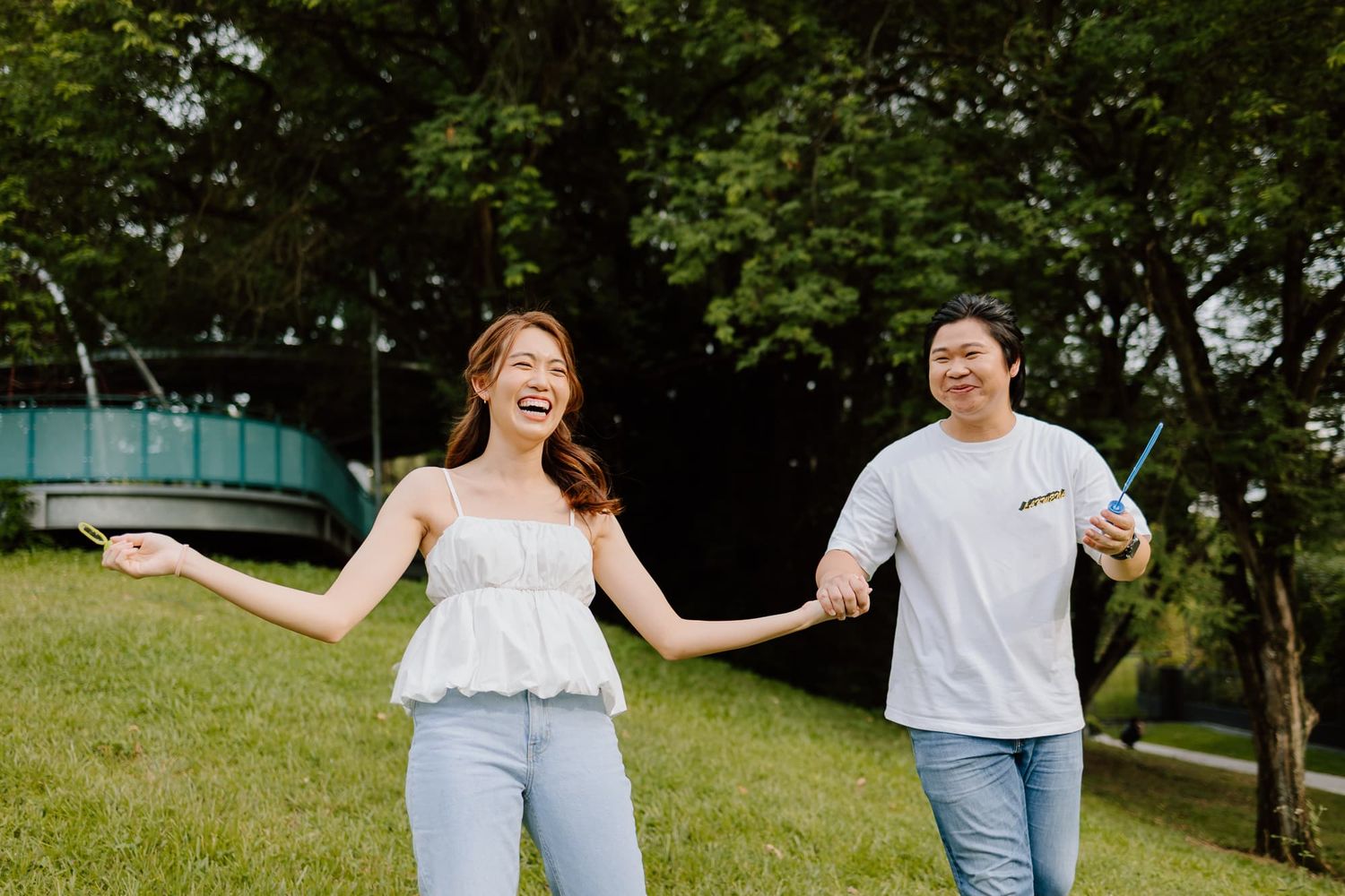 Joyful couple running and laughing together in green park setting.