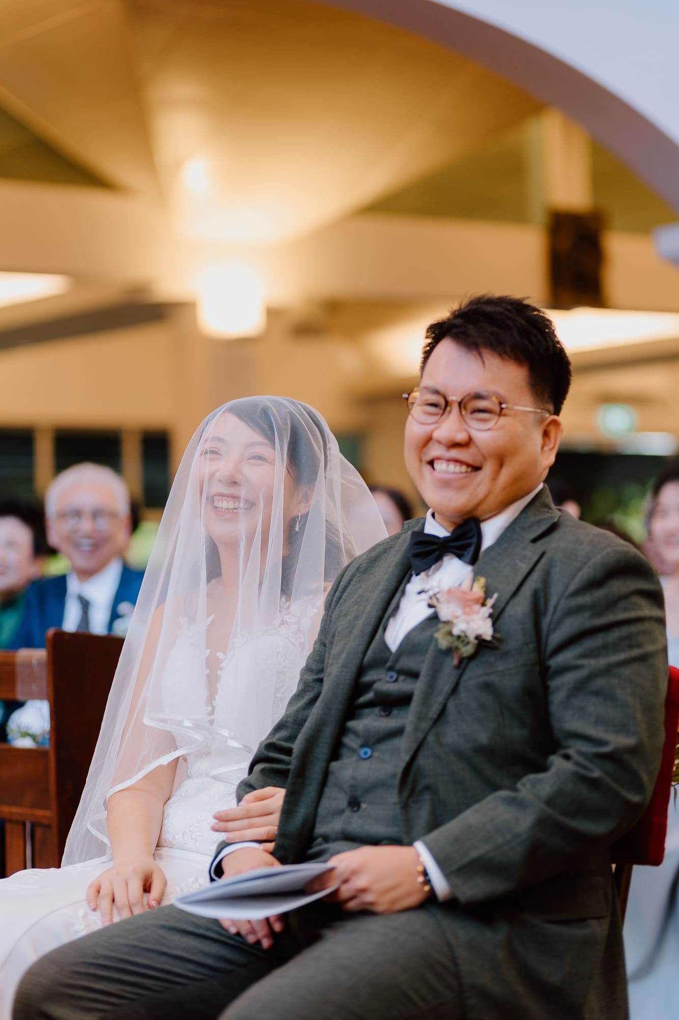 A joyful wedding ceremony moment showing a bride and groom sharing laughter while seated during their special day.
