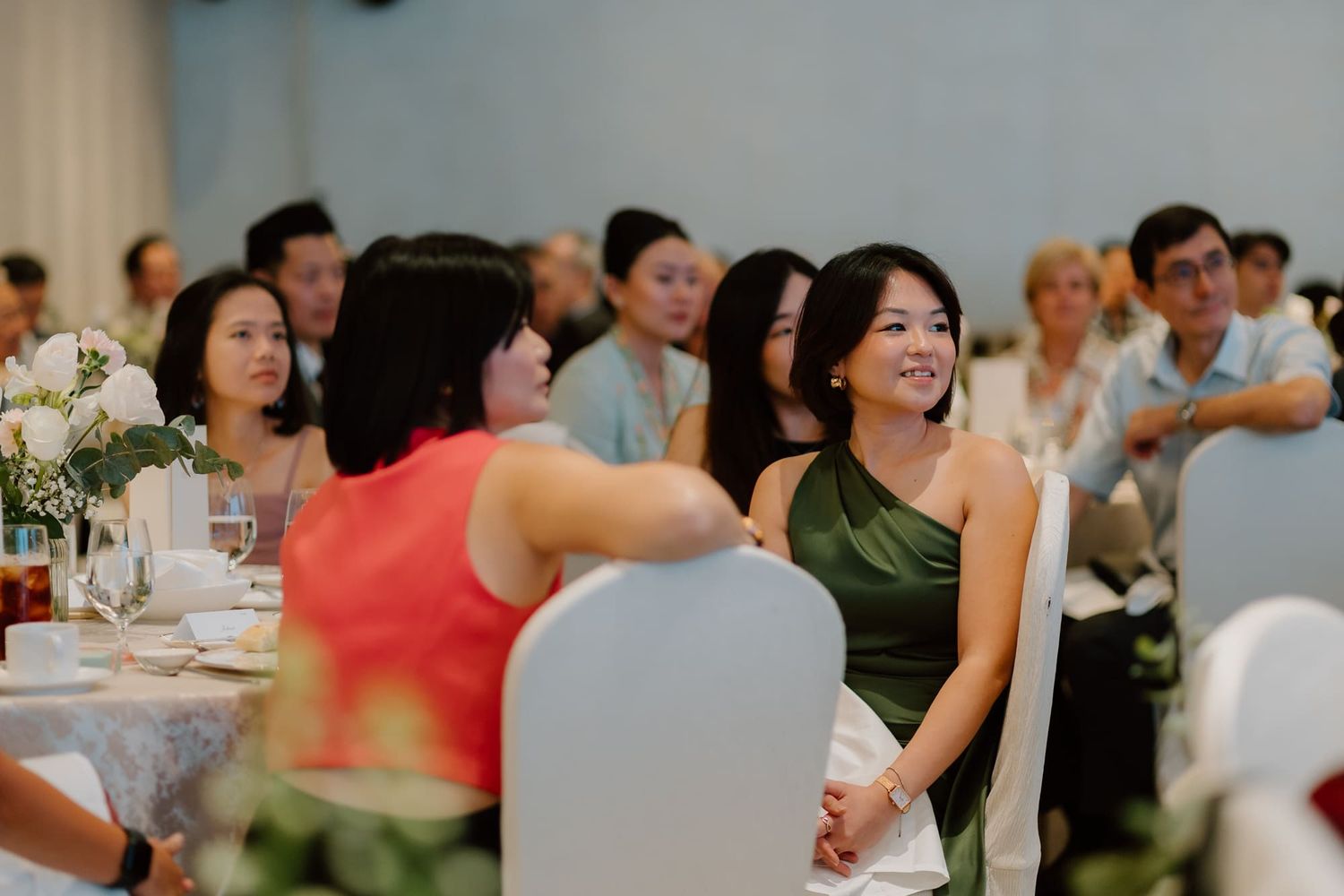 Wedding reception guests seated at round tables in an elegant banquet hall during a celebration.