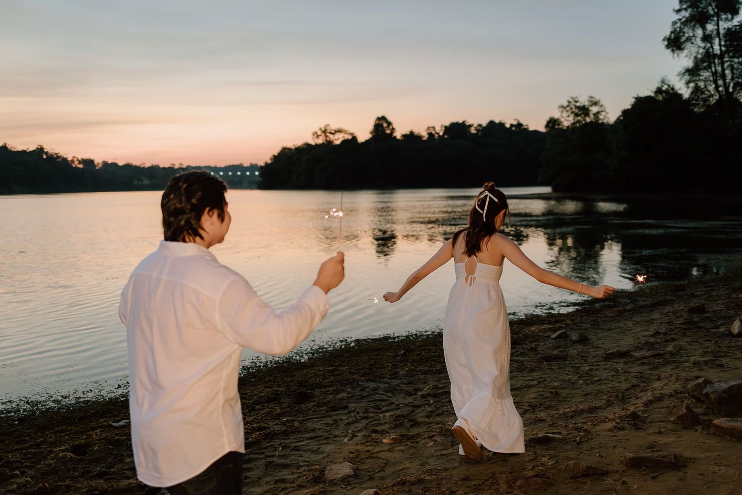 Couple posing with a golden sunset backdrop at a lakeside location.