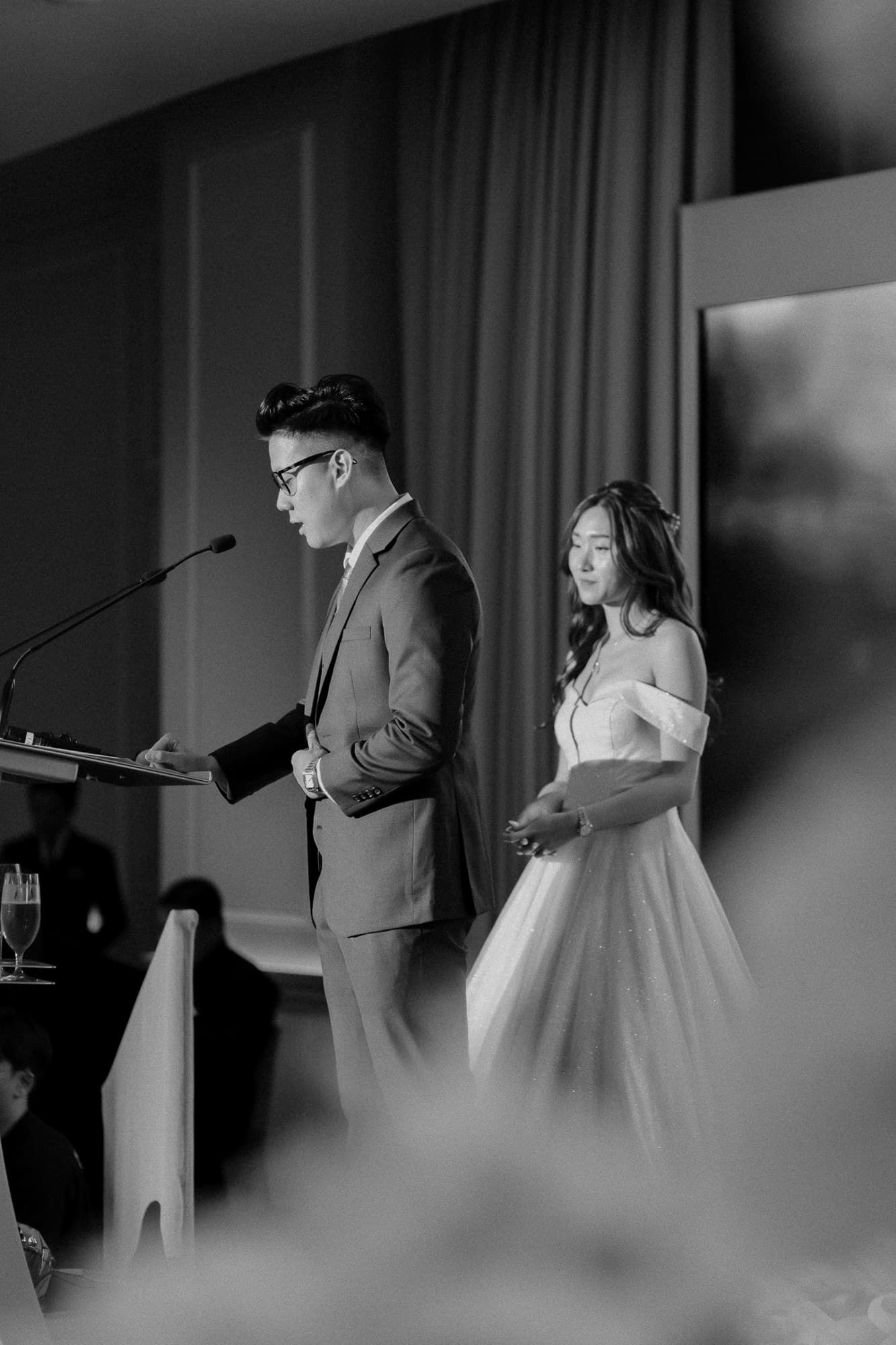 Black and white photo of wedding ceremony with dramatic lighting and microphone setup.
