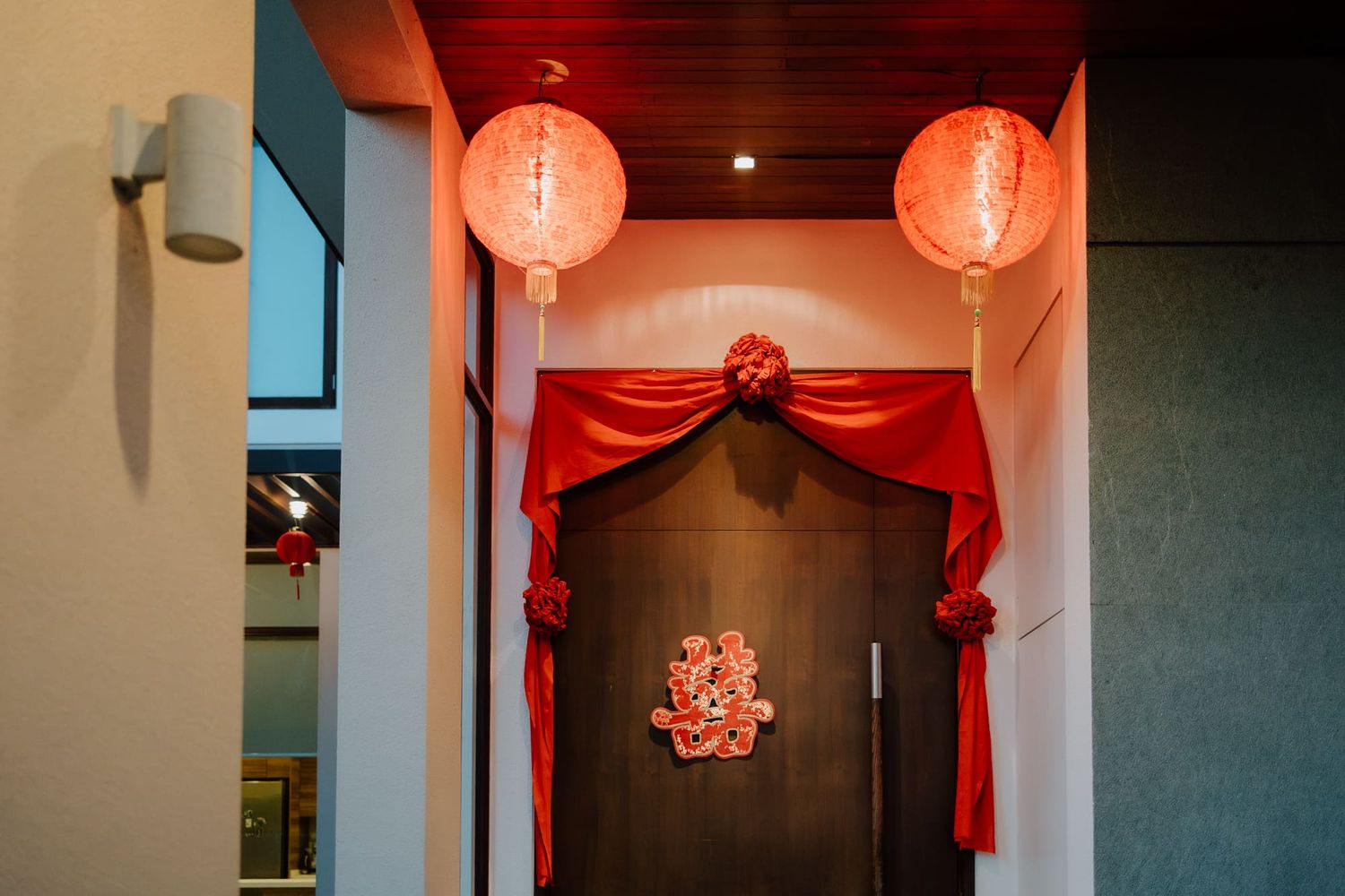 Red Chinese paper lanterns and fabric decorations hang from the ceiling in a dimly lit interior space.