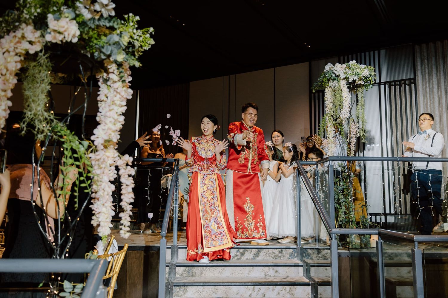 Wedding ceremony decorations feature elegant white floral arrangements and greenery along rustic wooden structures.