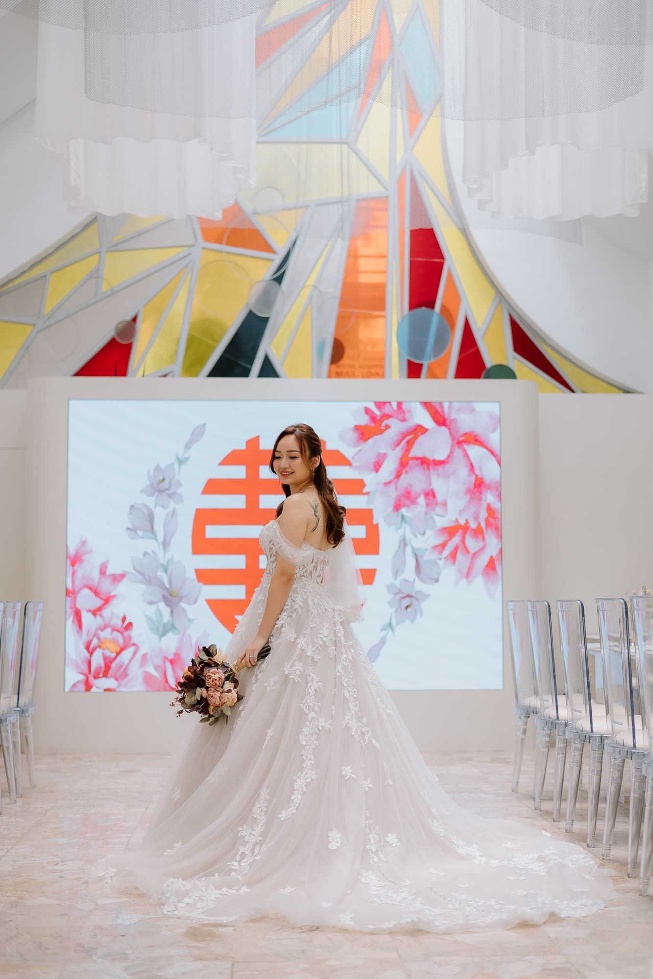 Bride in lace ballgown poses against modern geometric wall art and double happiness symbol.