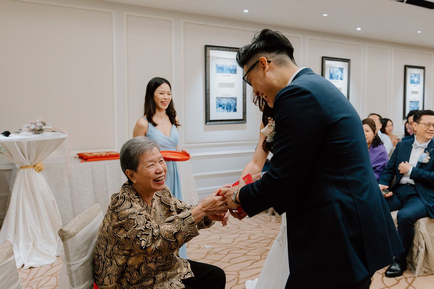 Wedding guests participate in a traditional tea ceremony during an intimate reception in an elegant event space.
