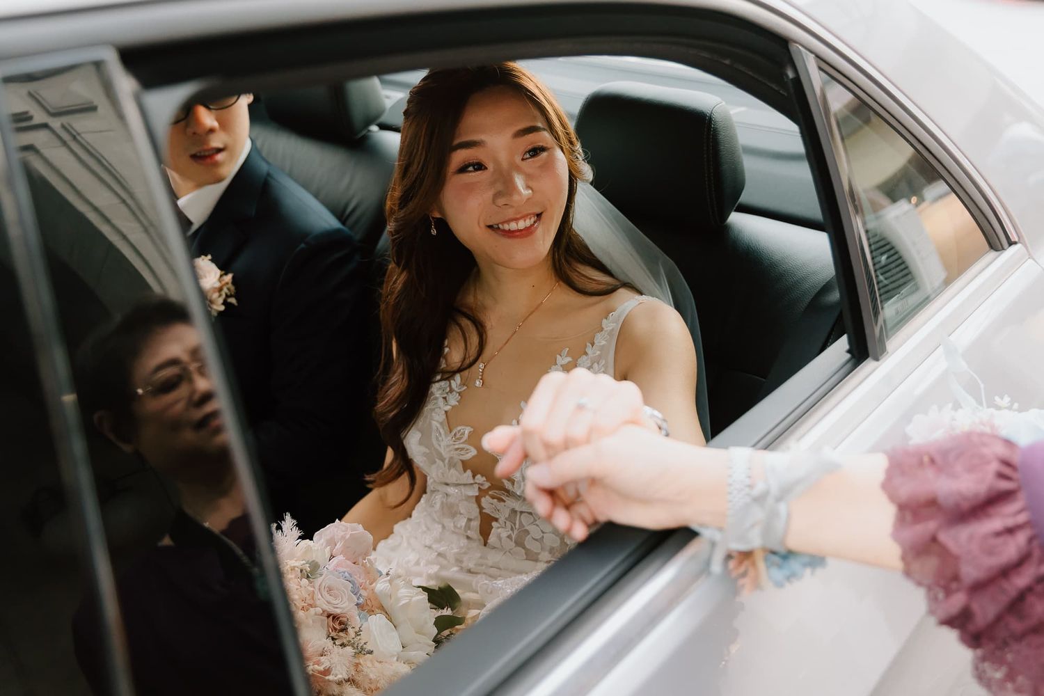 A view through a car window showing someone in a wedding dress.