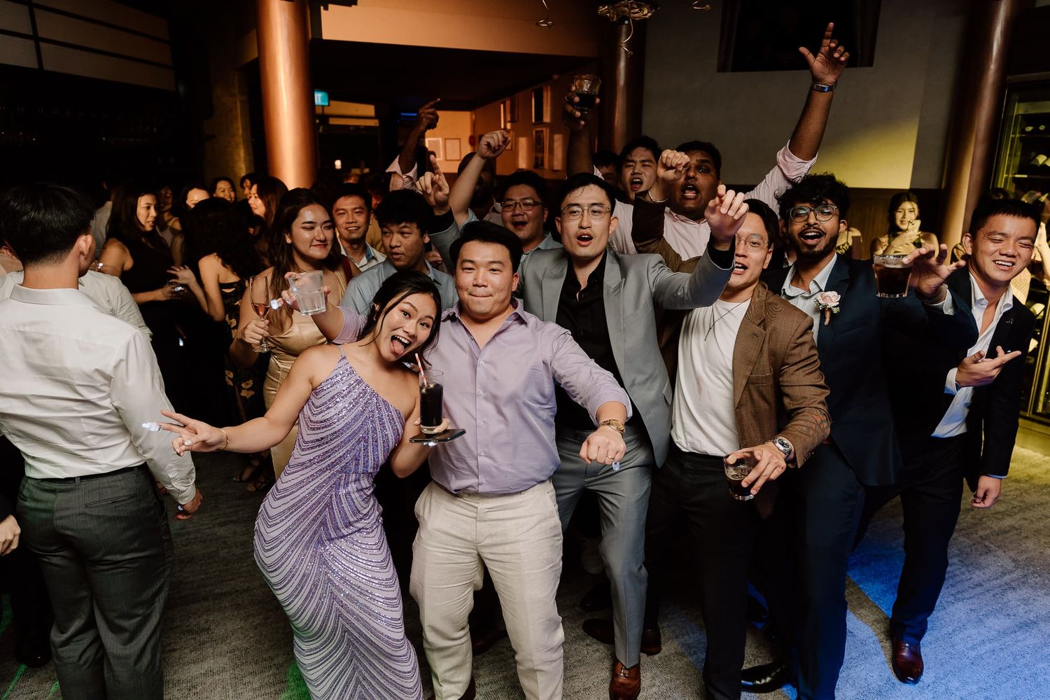 A group celebrating on a dance floor at a wedding reception with joyful expressions.