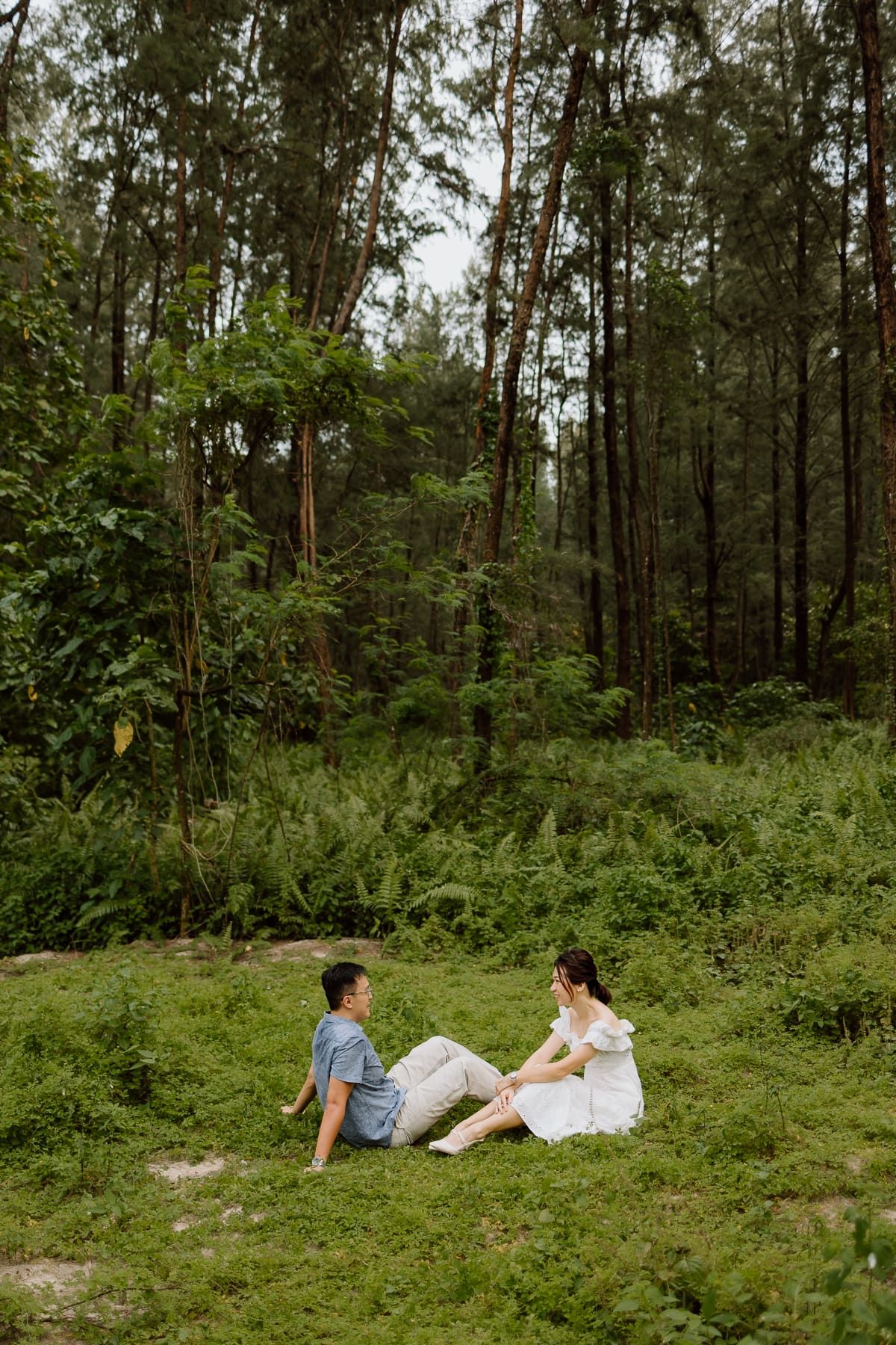 Couple relaxing together on grass in a serene forest setting.