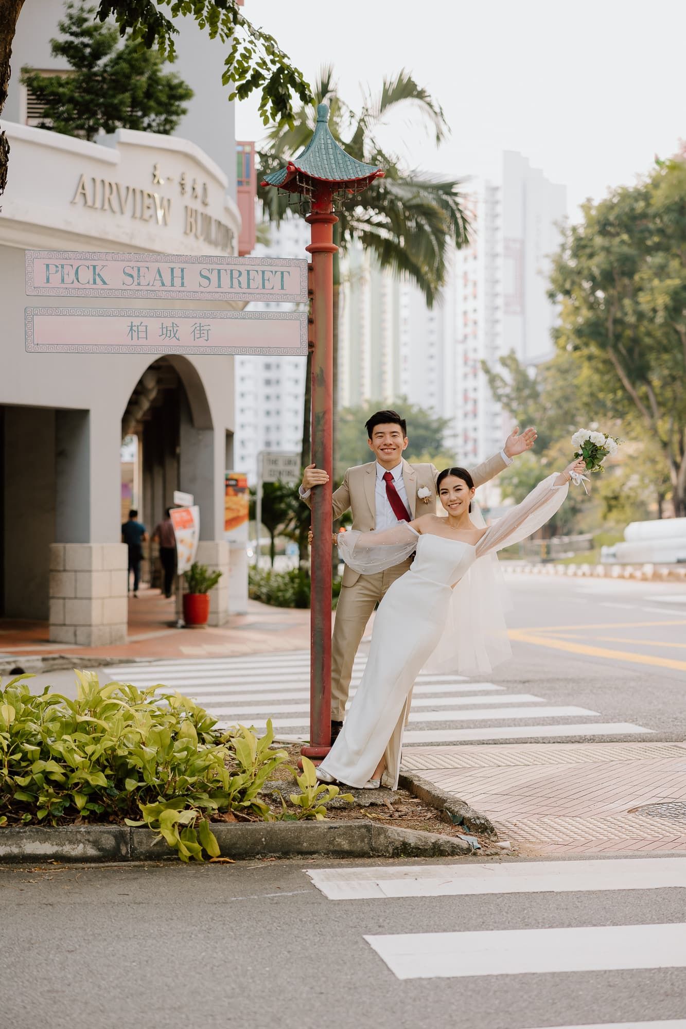 Wedding couple poses playfully by a street sign in an urban setting.