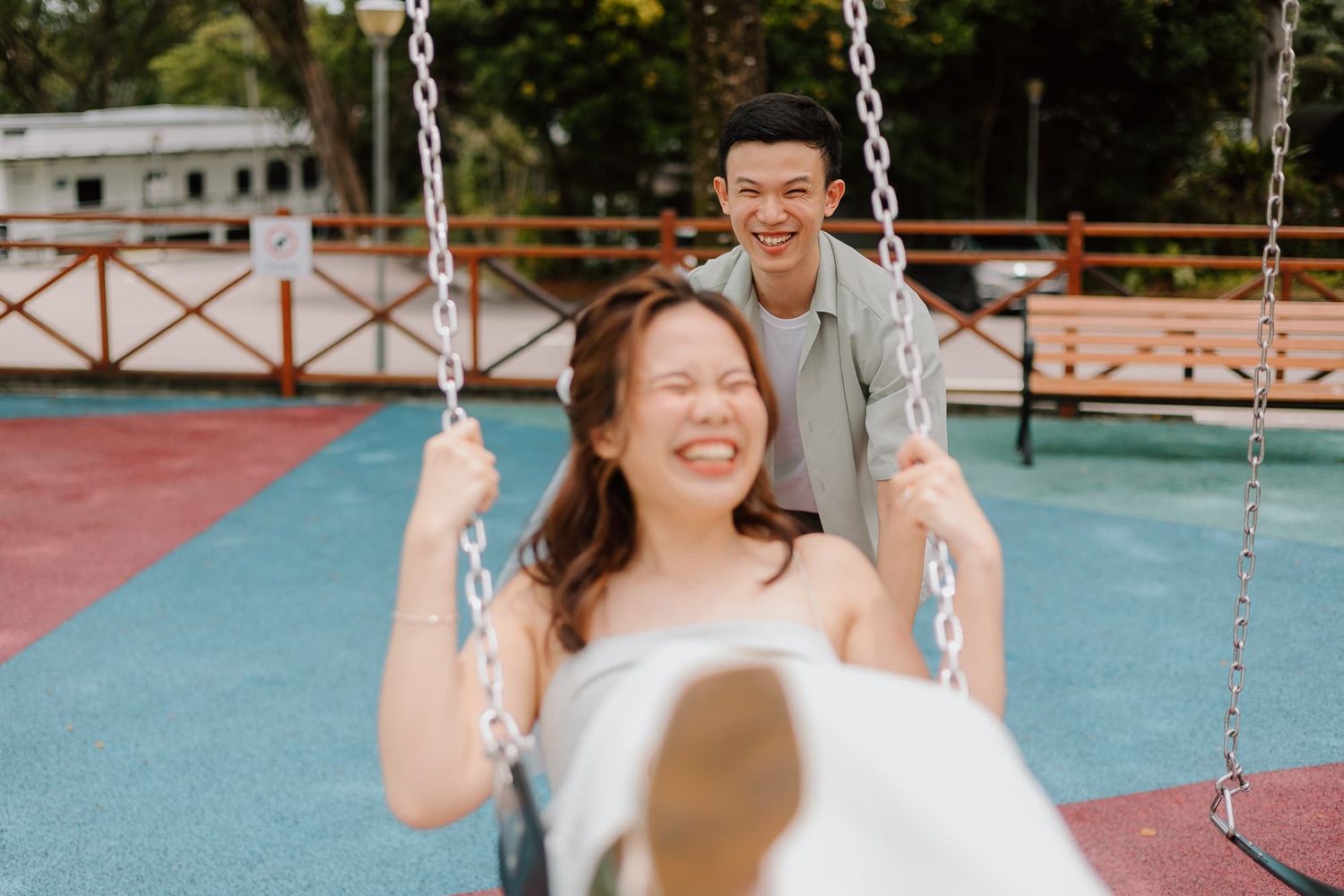 Playful moment at a playground with person pushing someone on a swing.