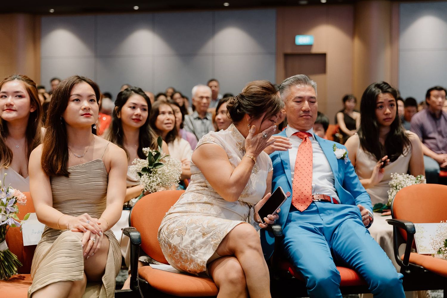 Wedding guests watch attentively during an indoor ceremony celebration.