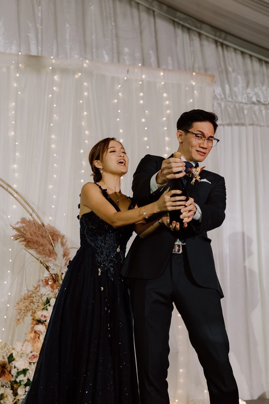 Two people in formal attire share a playful moment during an event.