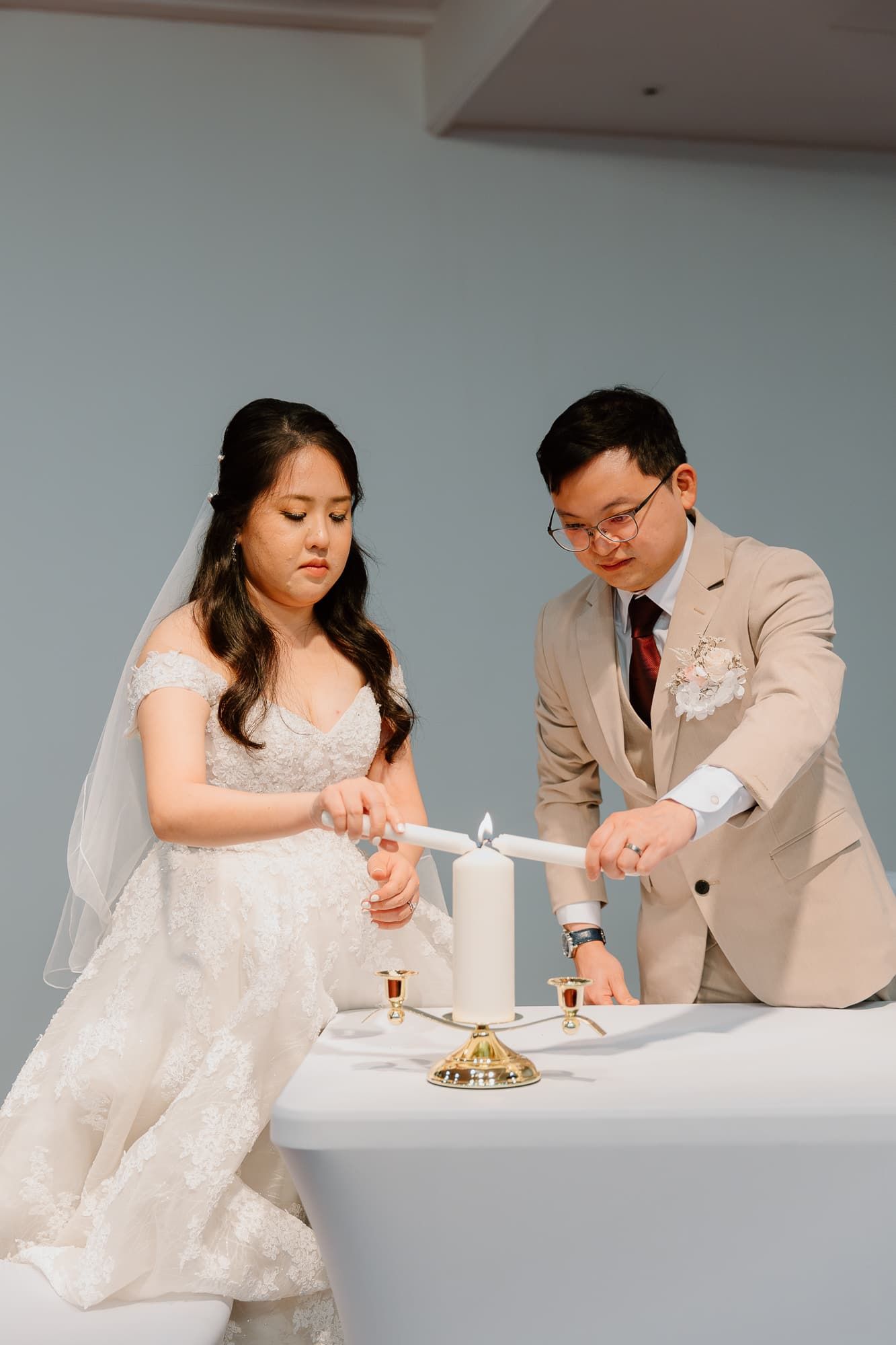 A wedding kiss moment in front of a modern wooden cross at a church altar.