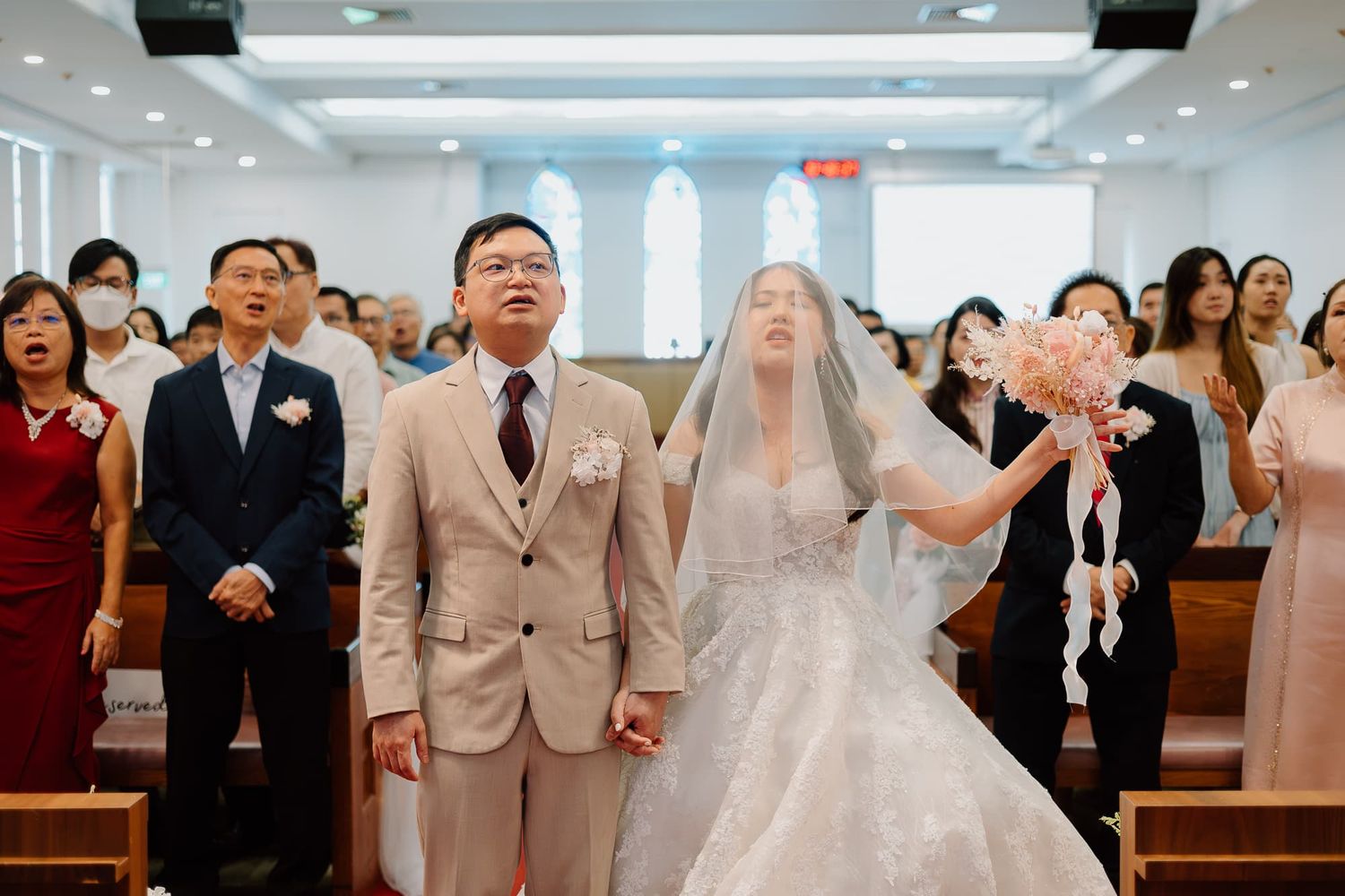 A wedding ceremony in progress in a modern church sanctuary filled with guests.