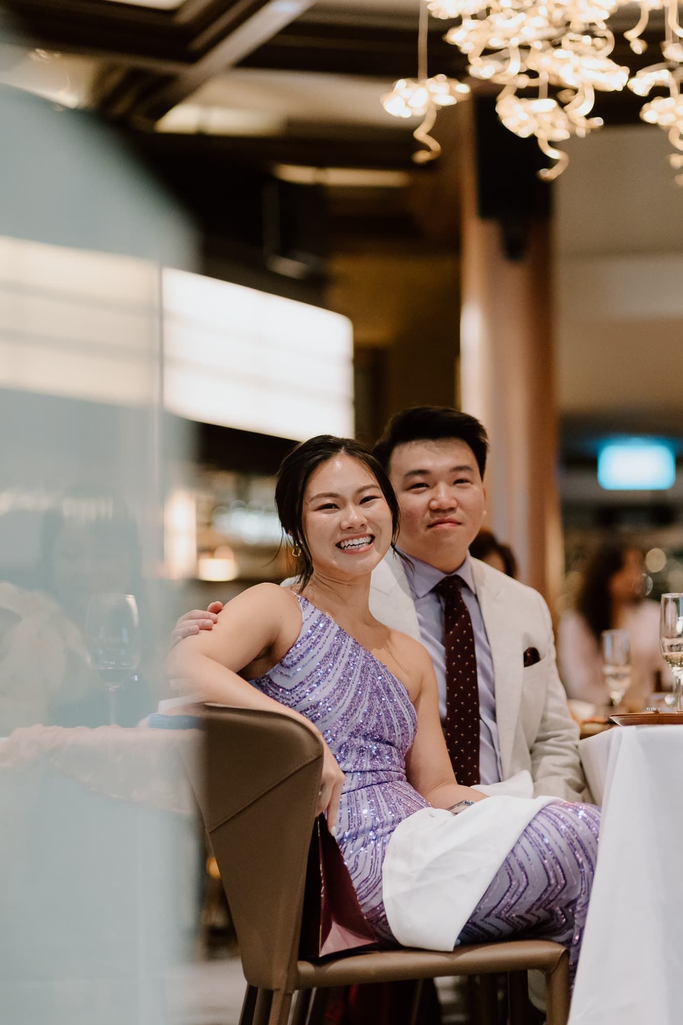 Guests share a candid moment at a wedding reception in an elegantly lit venue.