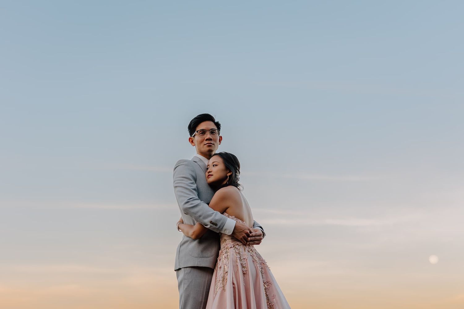 Romantic sunset photoshoot at an outdoor wedding venue against a blue sky.