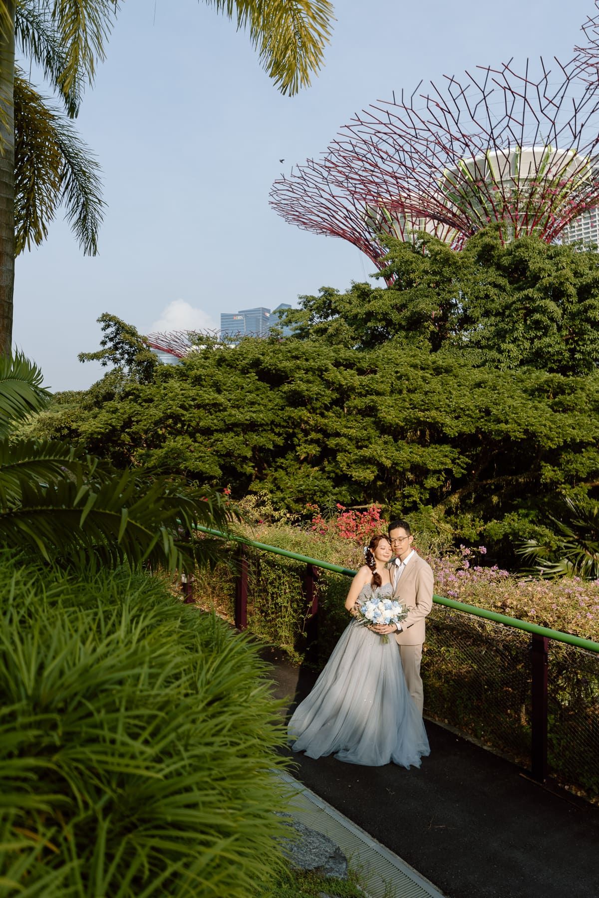A romantic wedding photo on a garden path with Supertrees and tropical foliage.