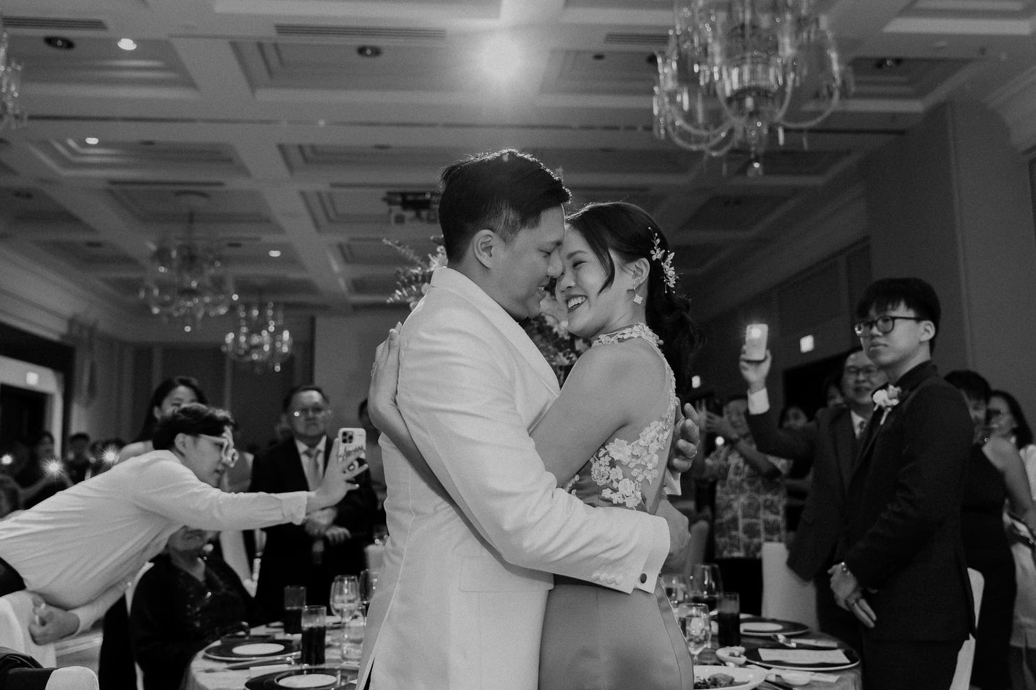 Black and white photo of dancing couple embracing at wedding reception.