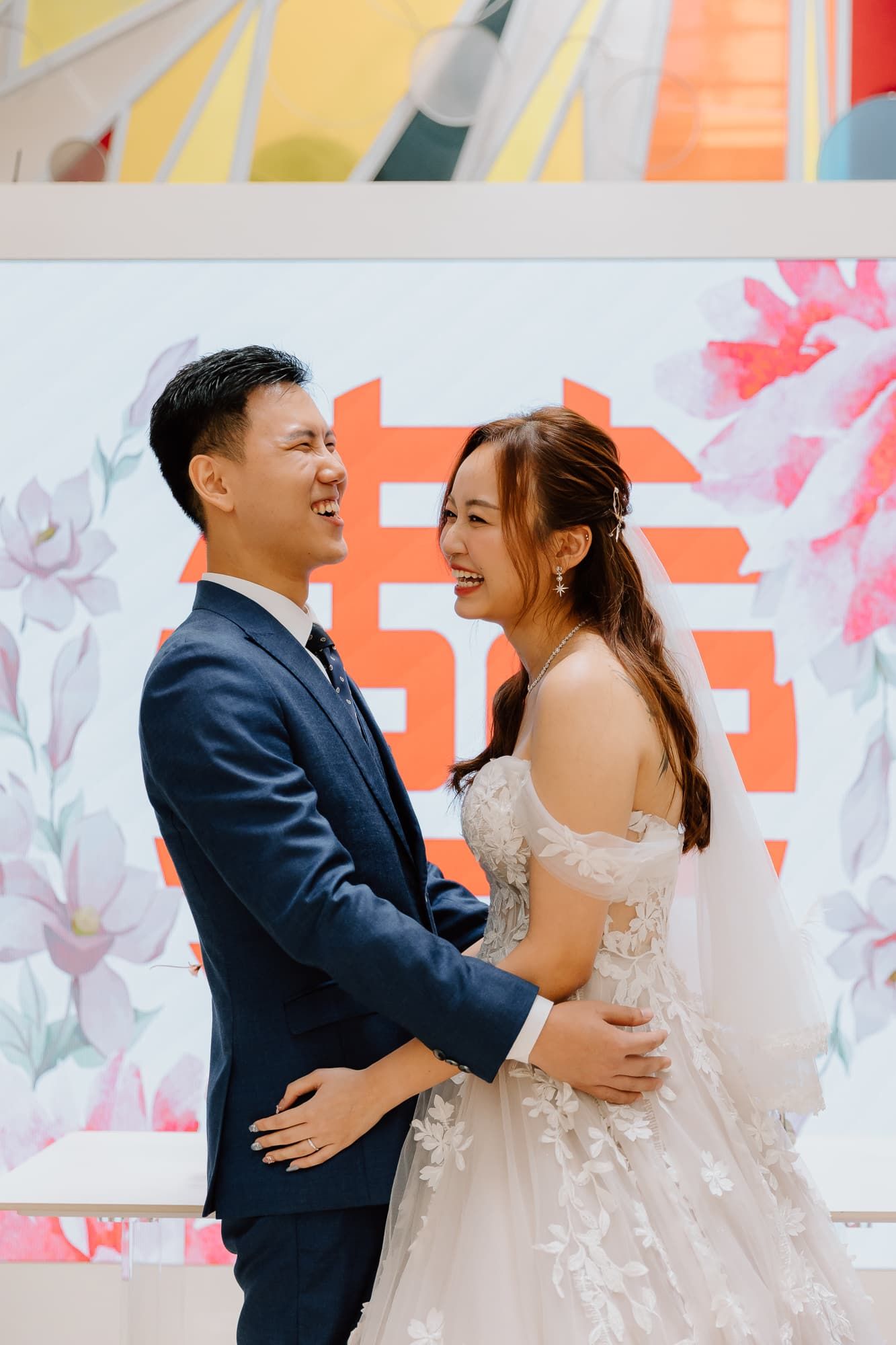 Romantic moment captured during wedding ceremony with floral and geometric wall art.