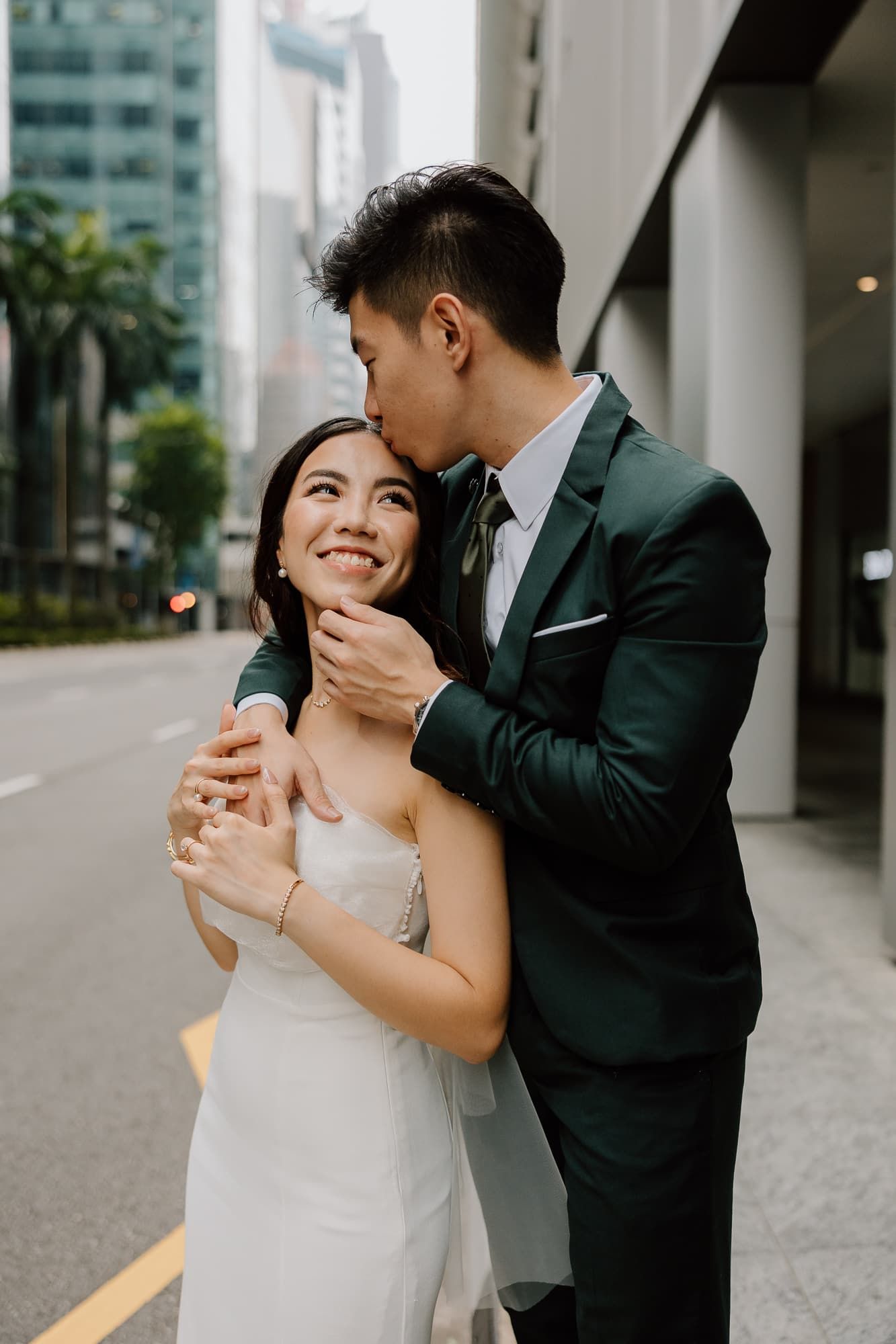 An intimate moment between newlyweds against an urban backdrop of modern buildings.