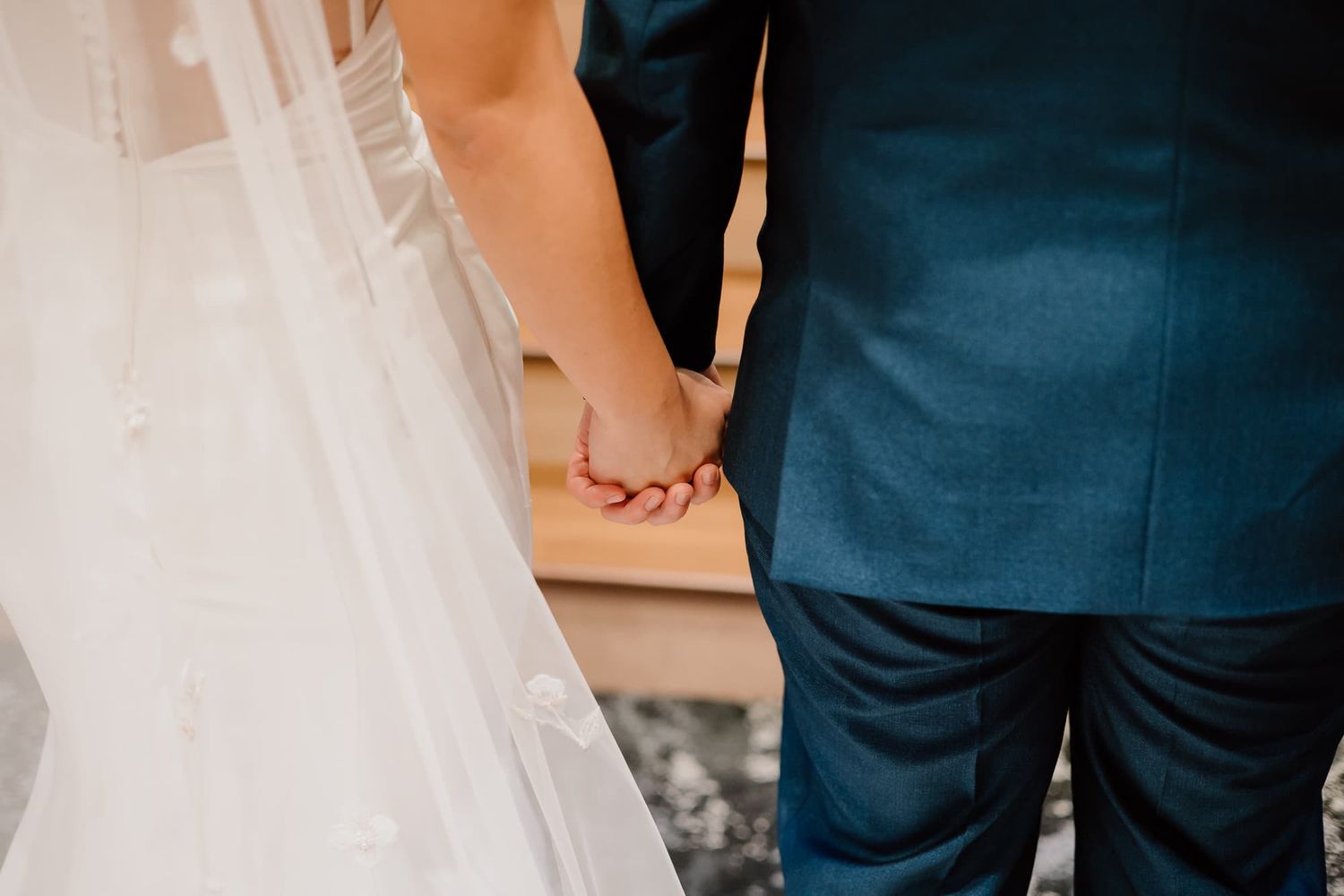 Close-up view of wedding dress details and formal attire during ceremony.