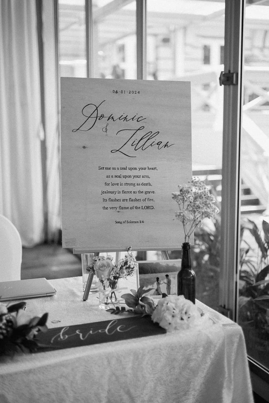 Wedding reception place cards and floral decorations displayed on a white table with natural lighting.
