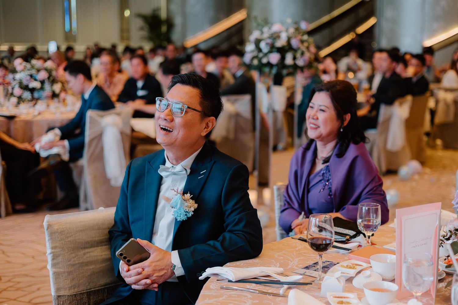 Wedding reception guests seated at tables during formal dinner celebration.
