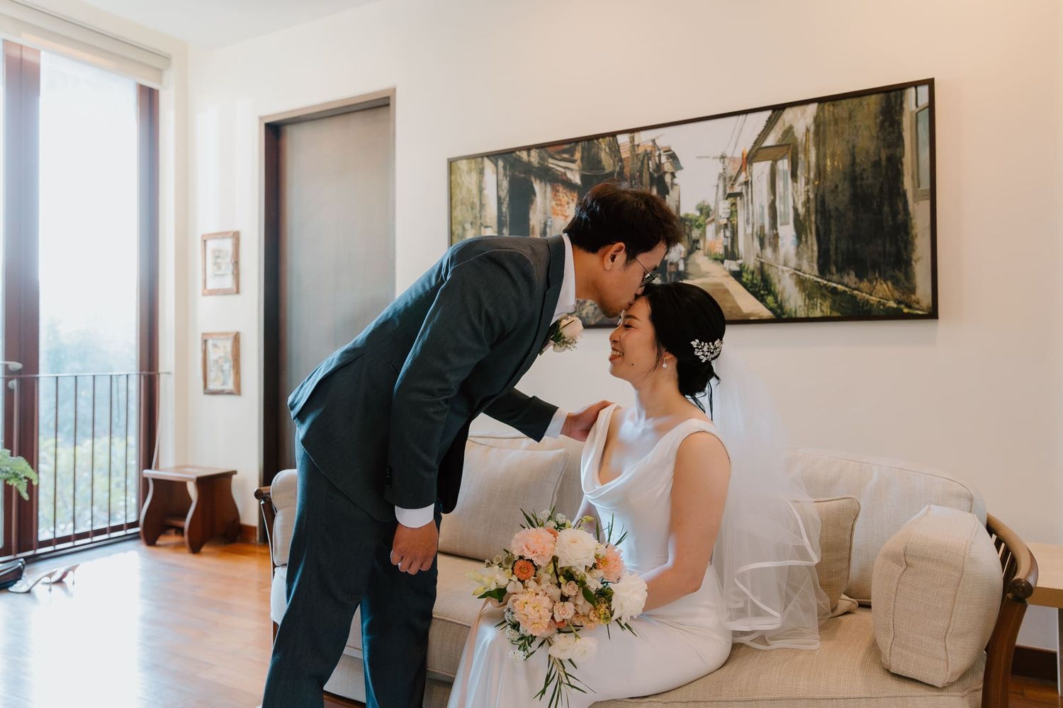 A panoramic view of a wedding couple in a bright white room with artwork on the walls during their ceremony.