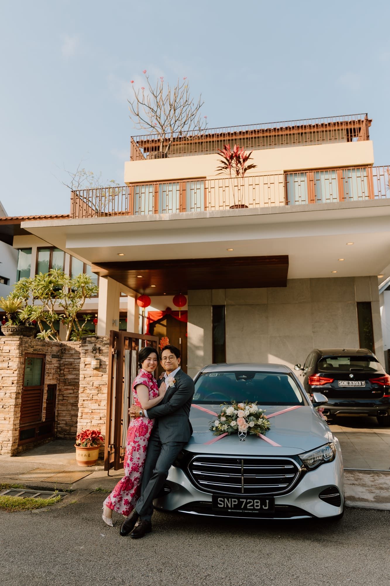 Decorated luxury car with flowers parked in front of modern house entrance with Chinese lanterns.