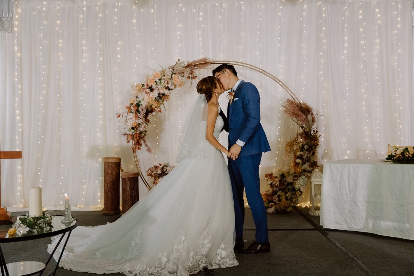A romantic first look moment between newlyweds in a white-draped venue with twinkle lights.