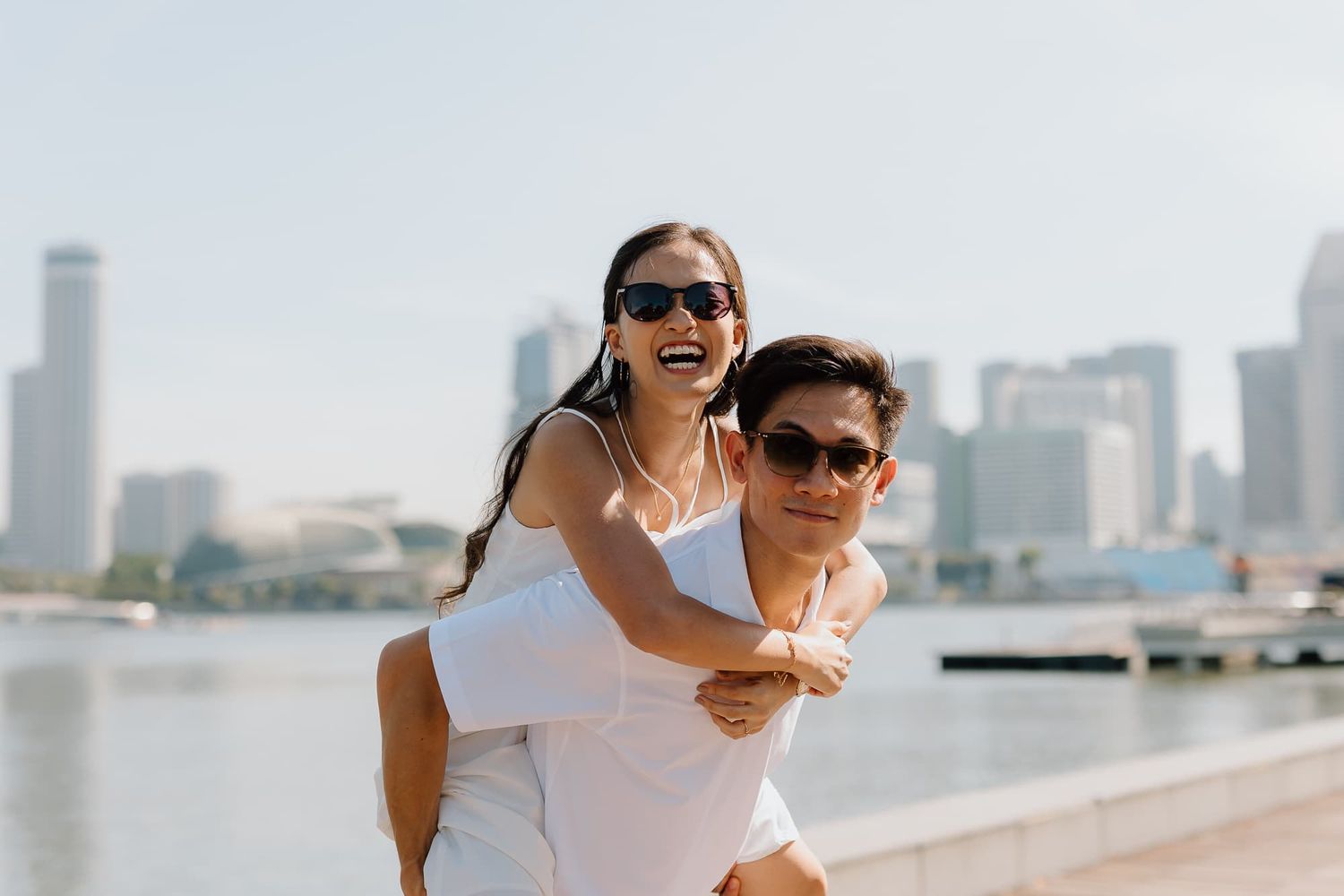 A joyful piggyback ride along the waterfront with city skyline in the background.