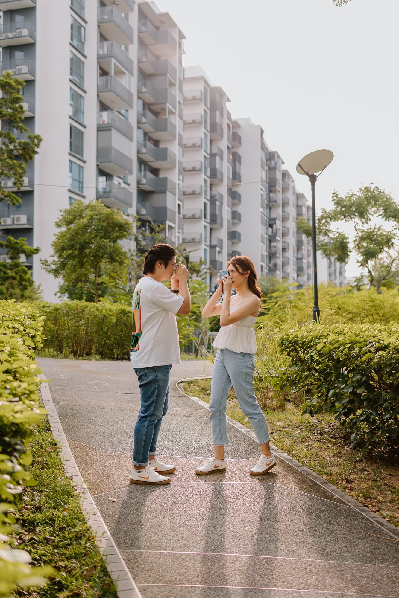 Couple having fun on pathway with residential buildings in background.
