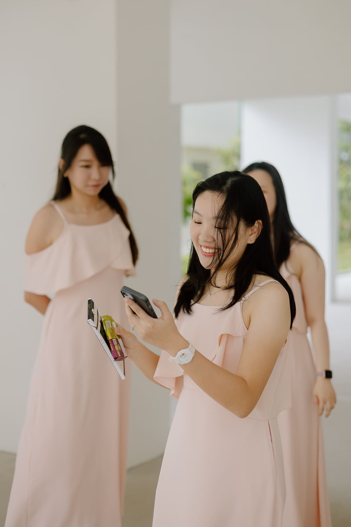 Bridesmaids in soft pink dresses sharing a moment during wedding preparations.