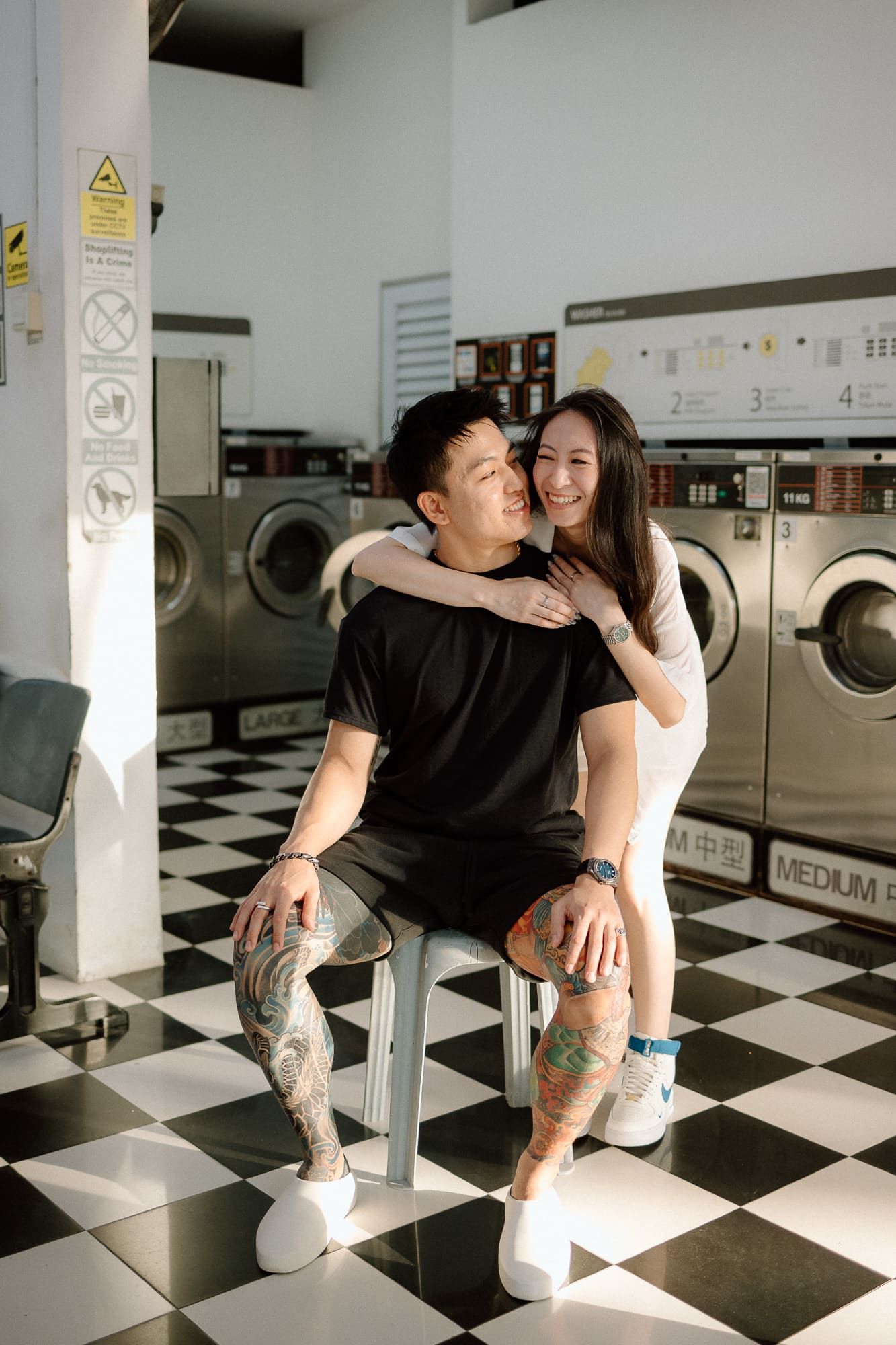 A couple shares intimate moments in a checkered floor laundromat with washing machines in the background.