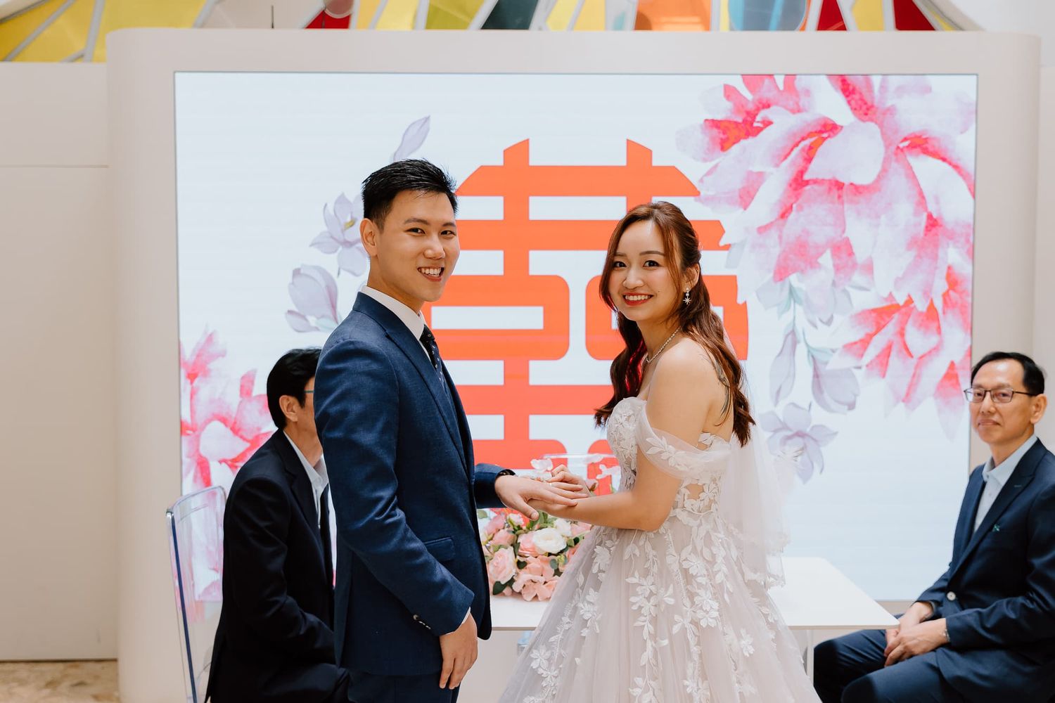 Celebratory gathering with guests seated at tables decorated with pink floral centerpieces.