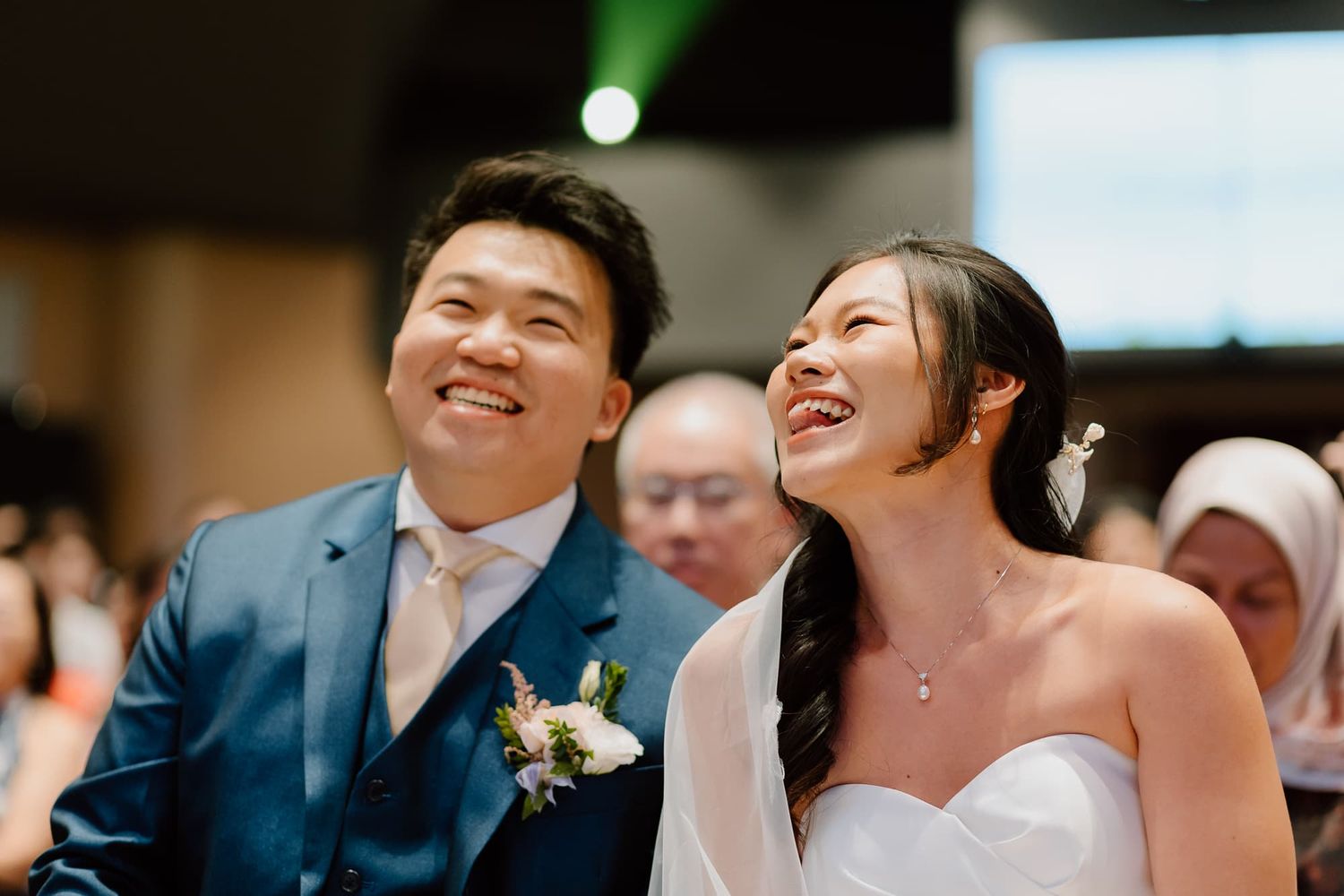 A couple laughs joyfully during their wedding ceremony while surrounded by guests.