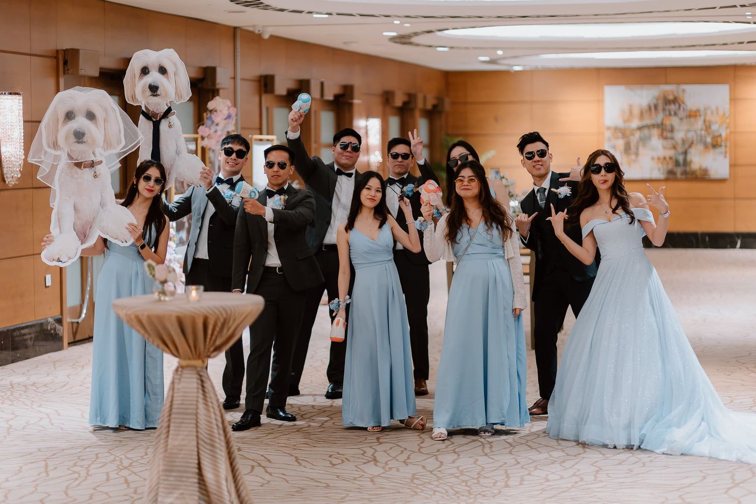 Wedding party in blue dresses and formal attire pose together for group photo.