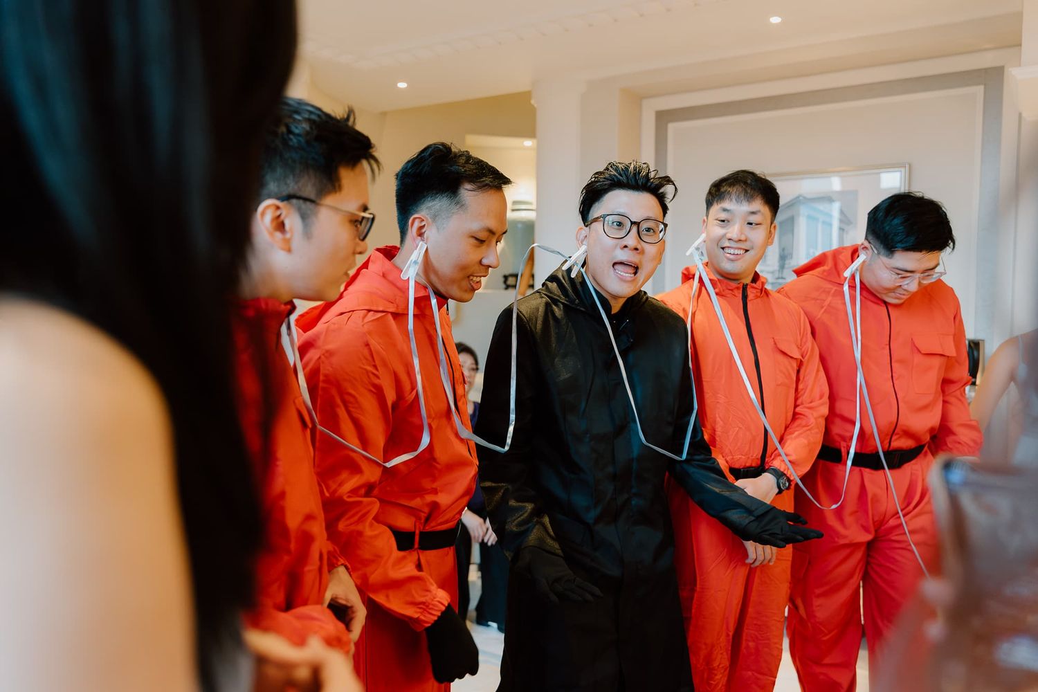 Wedding party members in bright red outfits gathered together indoors.