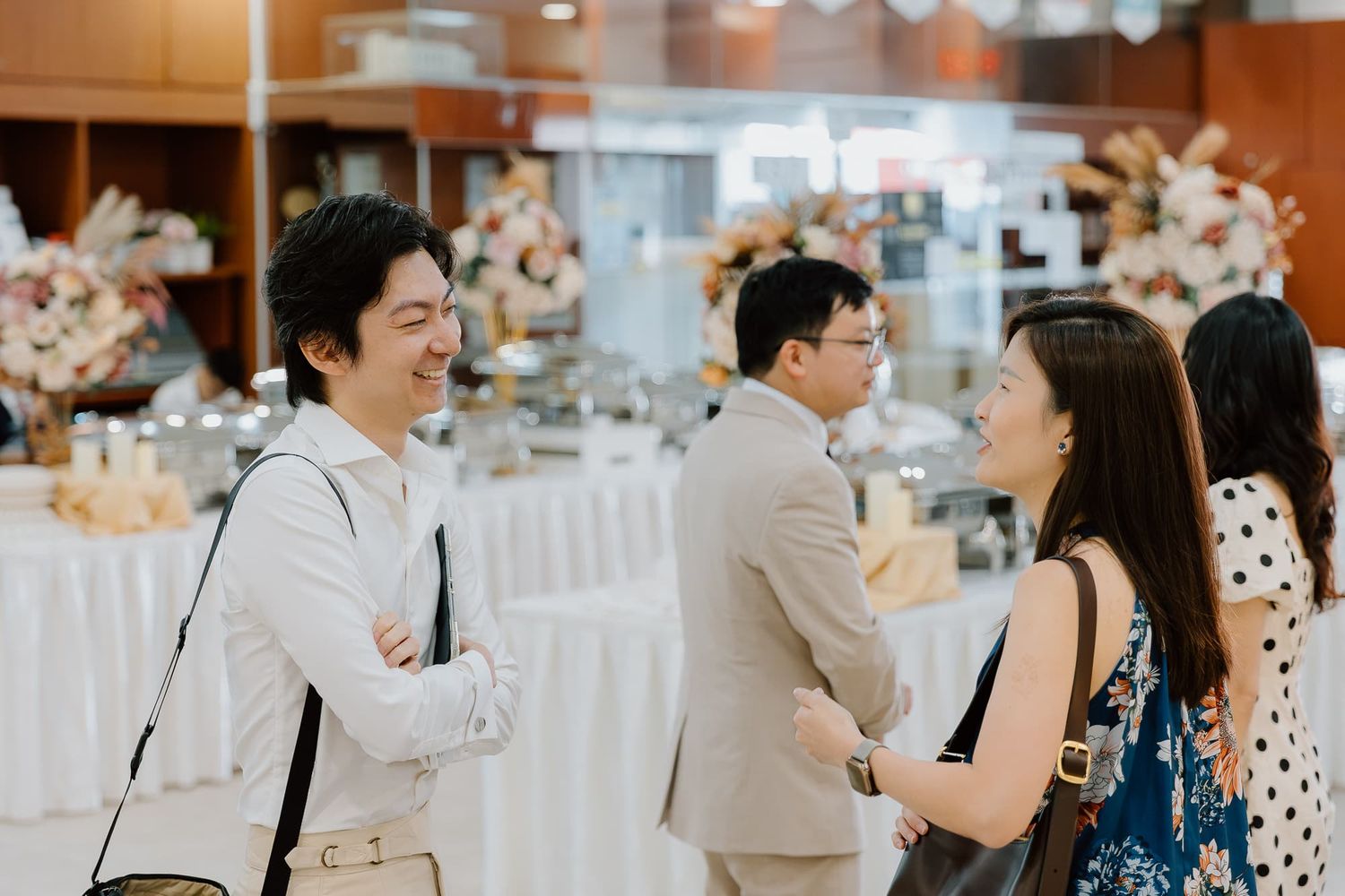 Wedding guests mingling and socializing at an indoor reception venue.