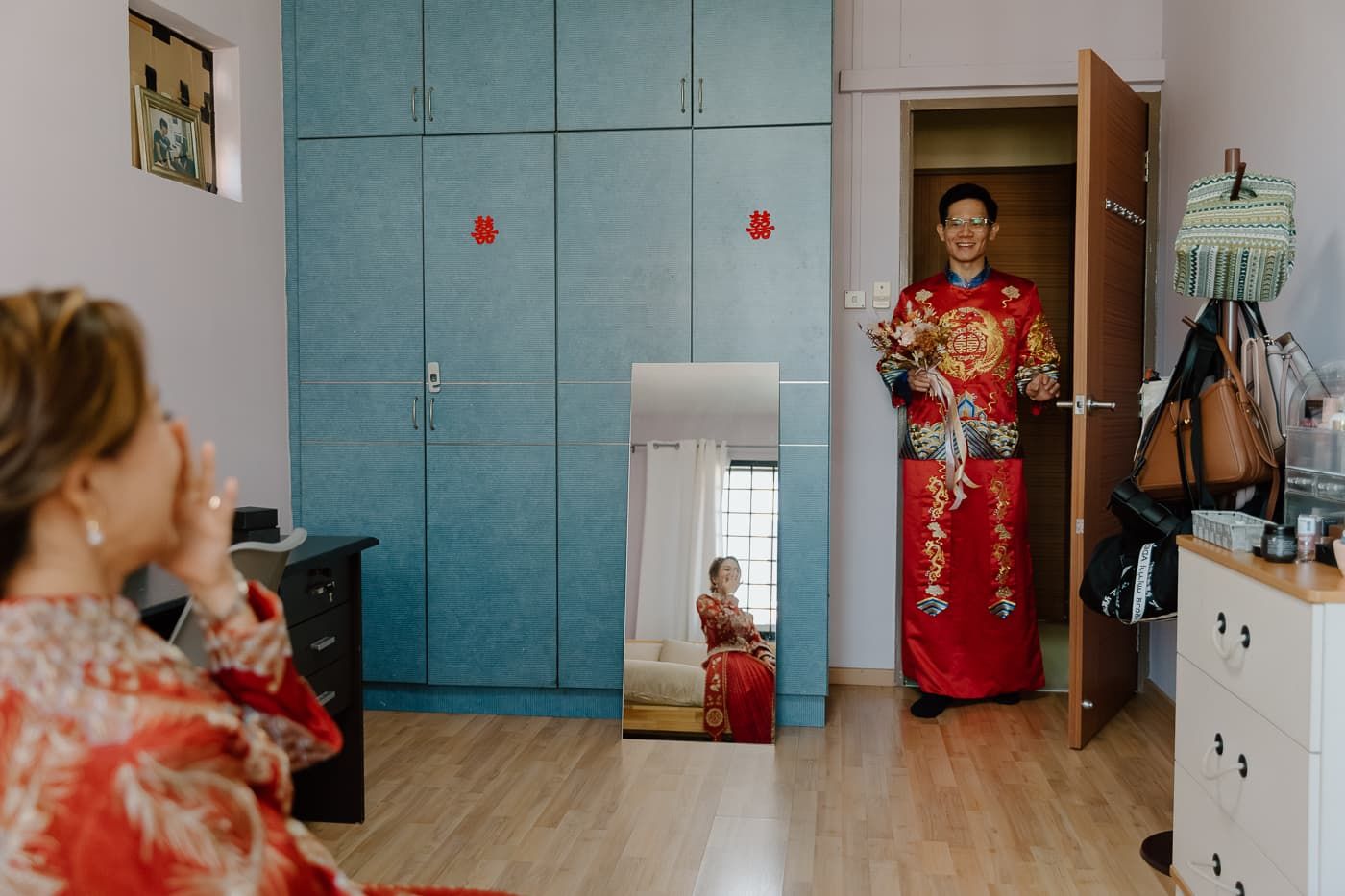 Red traditional Chinese wedding attire shown in mirror reflection and doorway.