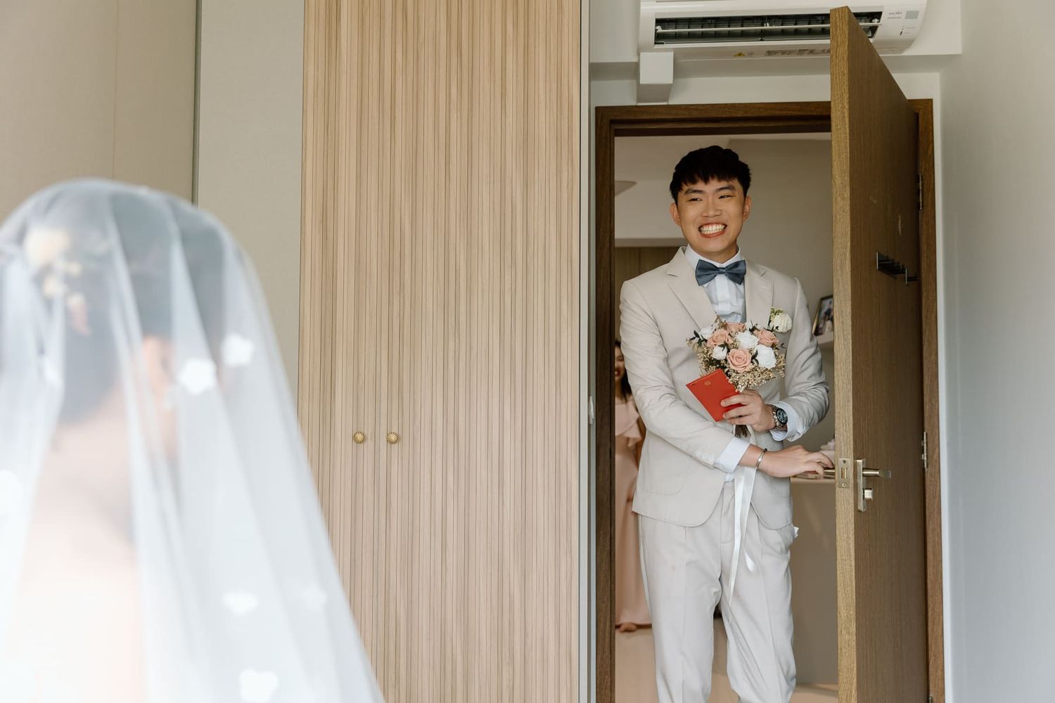 Person in light gray suit standing in doorway with traditional Chinese elements.
