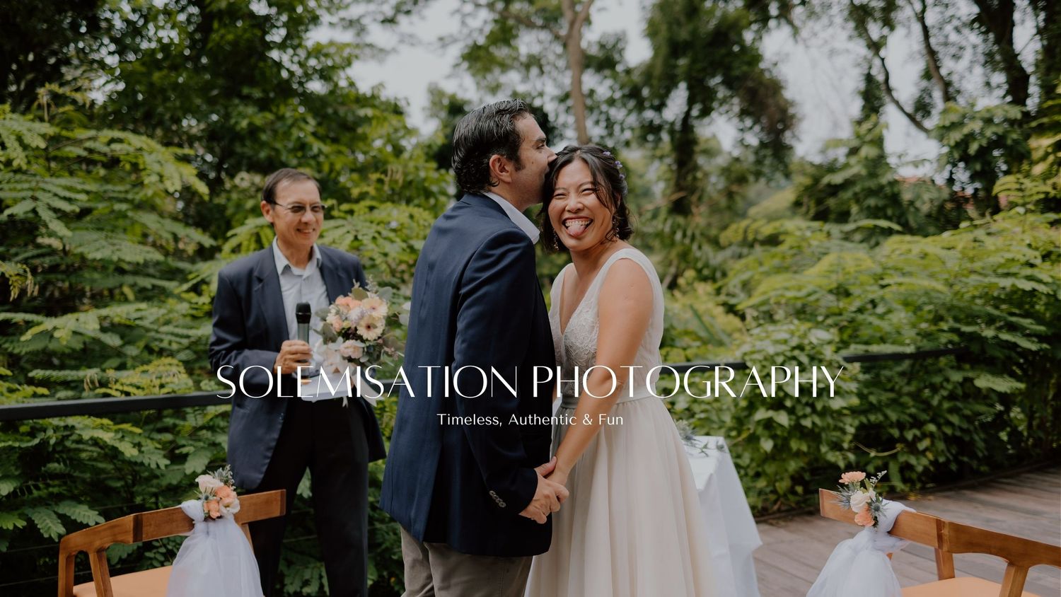 Wedding party celebrates on a wooden bridge surrounded by lush greenery during a summer celebration.