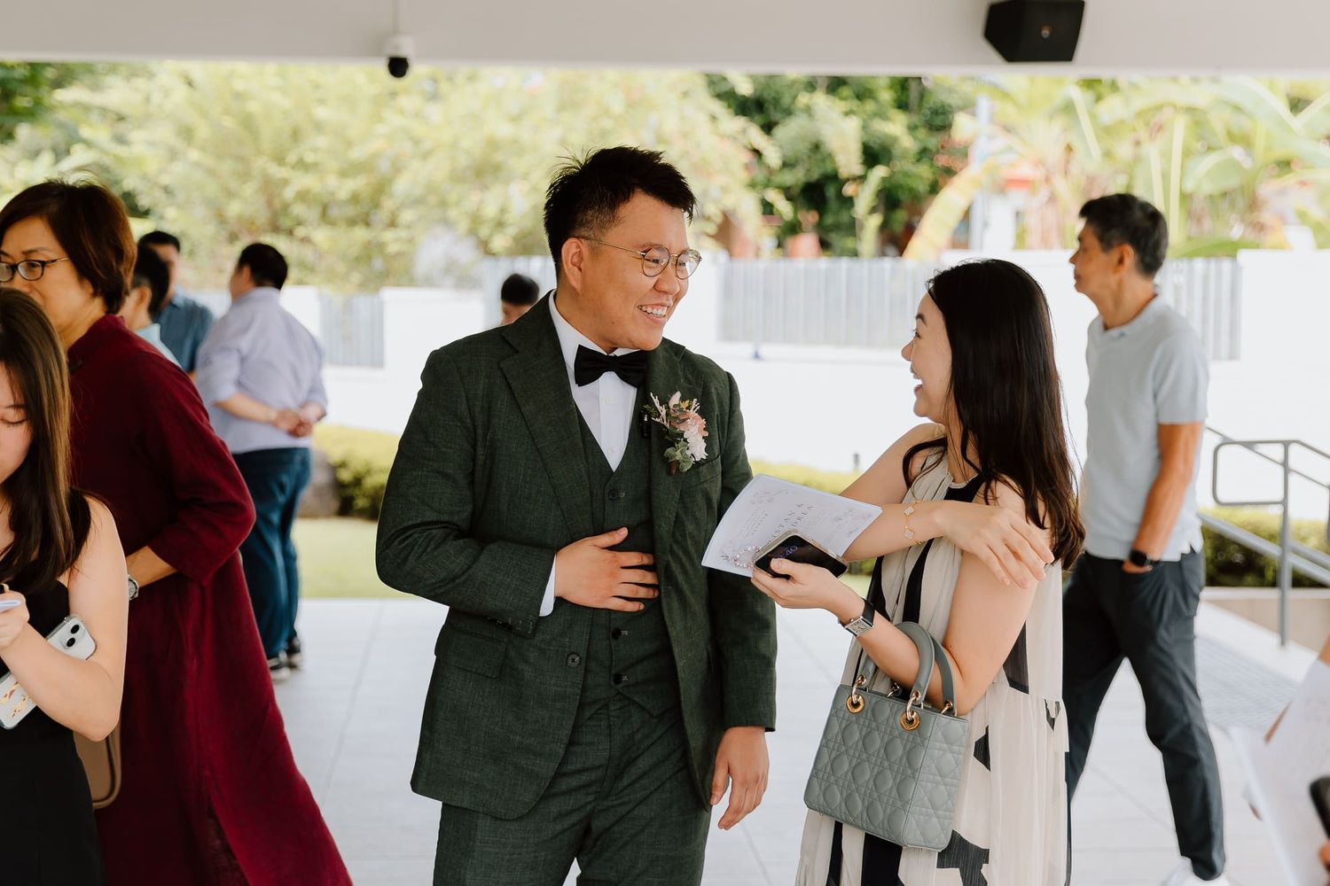 Wedding party and guests hugging and greeting each other at a venue entrance.