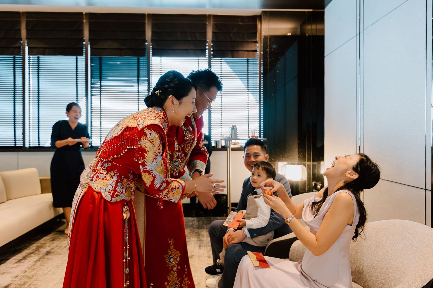 Traditional Chinese wedding celebration shows people interacting and laughing in a modern indoor setting.