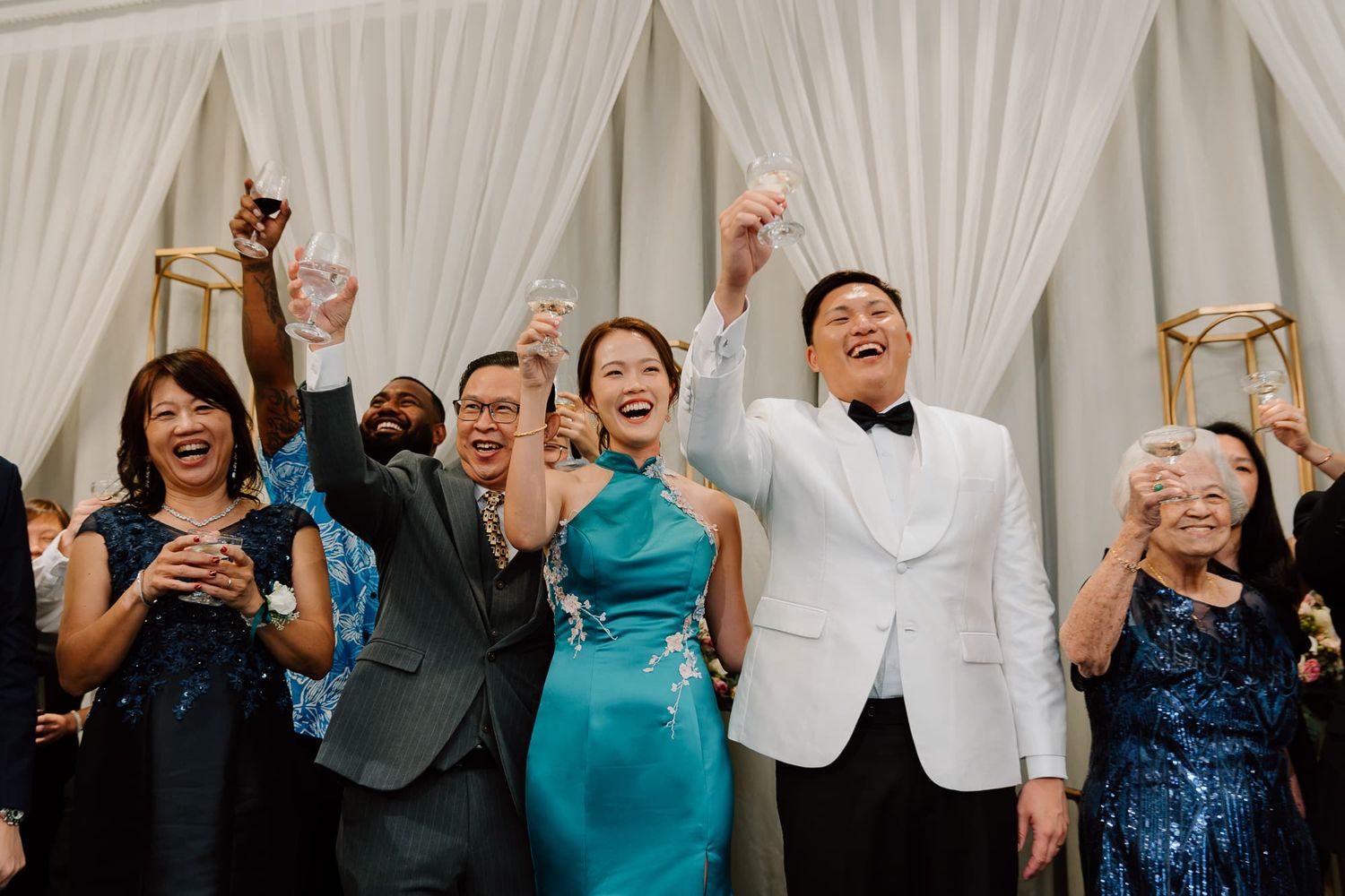 Guests celebrate with raised arms during a wedding reception.