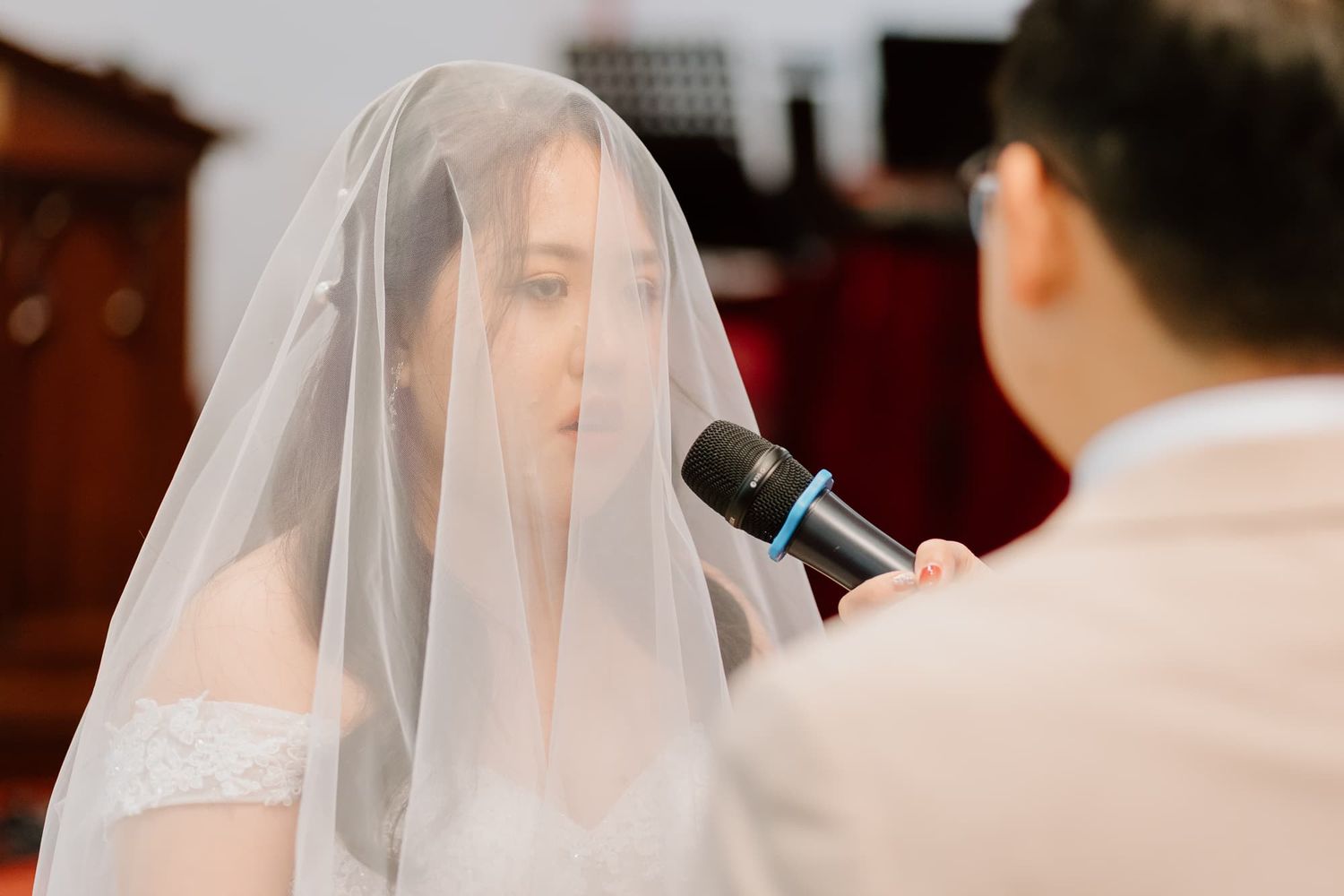 A wedding ceremony in progress with a minister officiating on a red-carpeted altar with a cross backdrop.