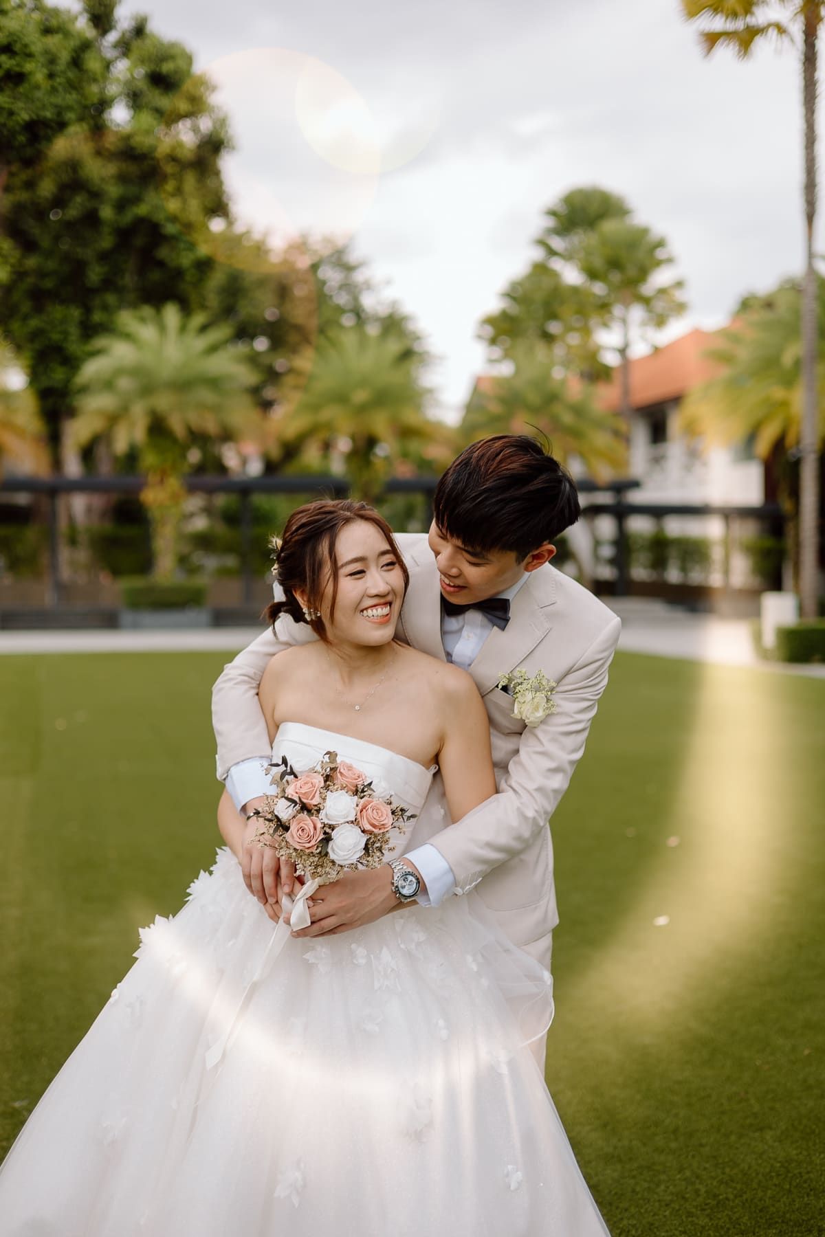 Intimate wedding photography session on a manicured lawn with palm trees.